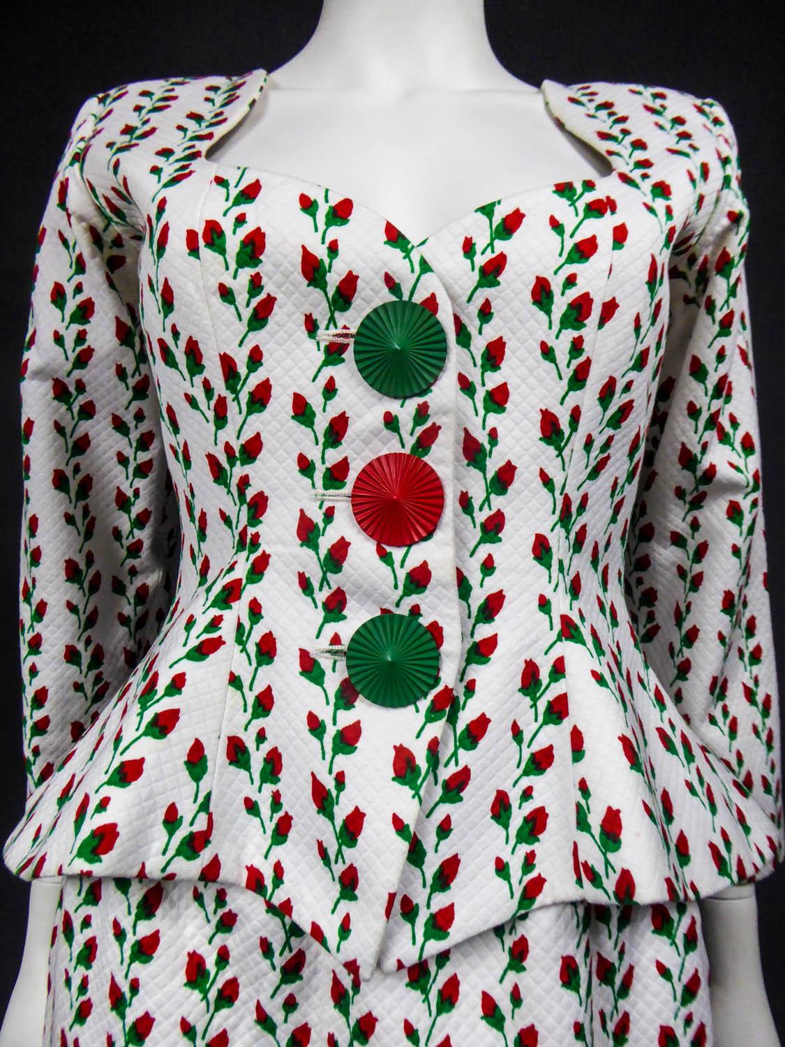 Circa 1980
France

Yves Saint Laurent Rive Gauche skirt suit in quilted white cotton piqué printed red roses buttons in garland. Slim-fitting jacket with a pronounced cut on the hips and a wavy neckline that enhances the chest. Small epaulettes and