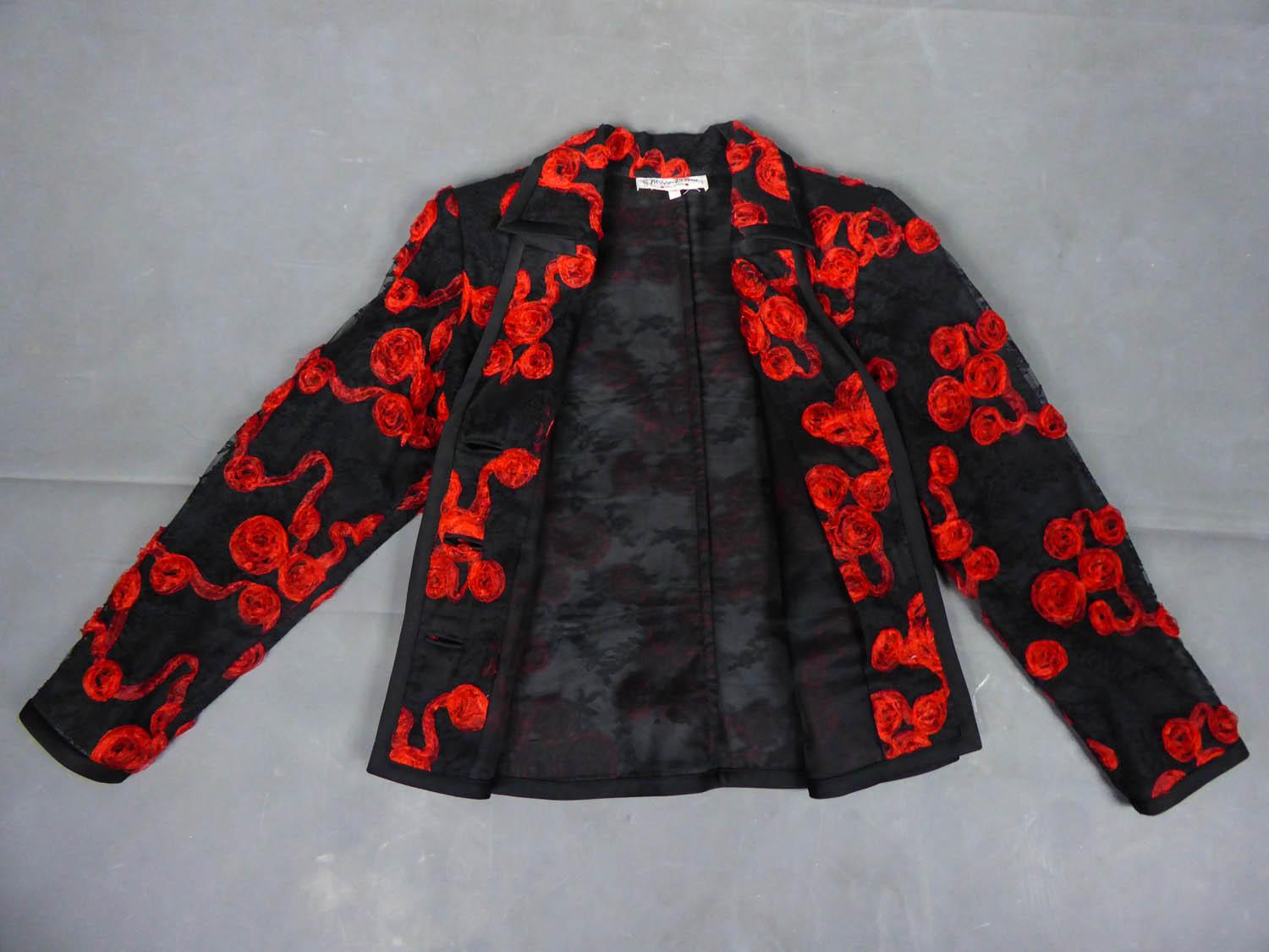 Circa 1980
France

Black lace jacket embroidered and applied with red flowers in organza ribbon. Fitted cut with wide collar, edge of the jacket in black satin. Front closure with three buttons representing a four-leaf clover. Label white background