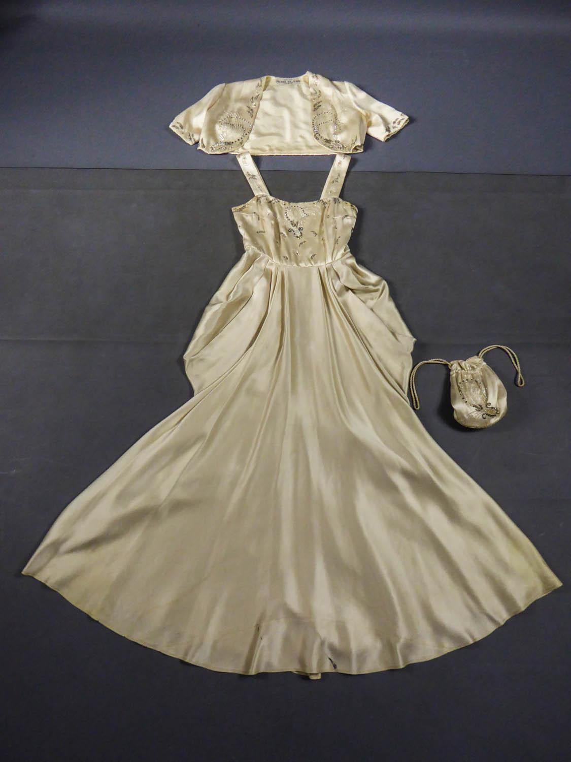 CIRCA 1950
Frankreich

Pierre Balmain Paris Abend- oder Festkleid mit passendem Bolero und Handtasche aus den 1950er Jahren. Elfenbeinfarbener Duchess-Satin, bestickt mit weißen und silbernen Tulpenperlen, Zuchtperlen, silbernen Pailletten und