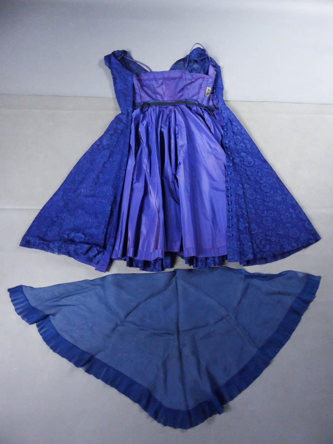 Circa 1950
France

A Louis Féraud Haute Couture dress in Calais lace with large bouquets of navy blue flowers dating from the early 50s. Dress with flared corolle skirt from the waist with a navy blue tulle underskirt and a purple taffeta slip