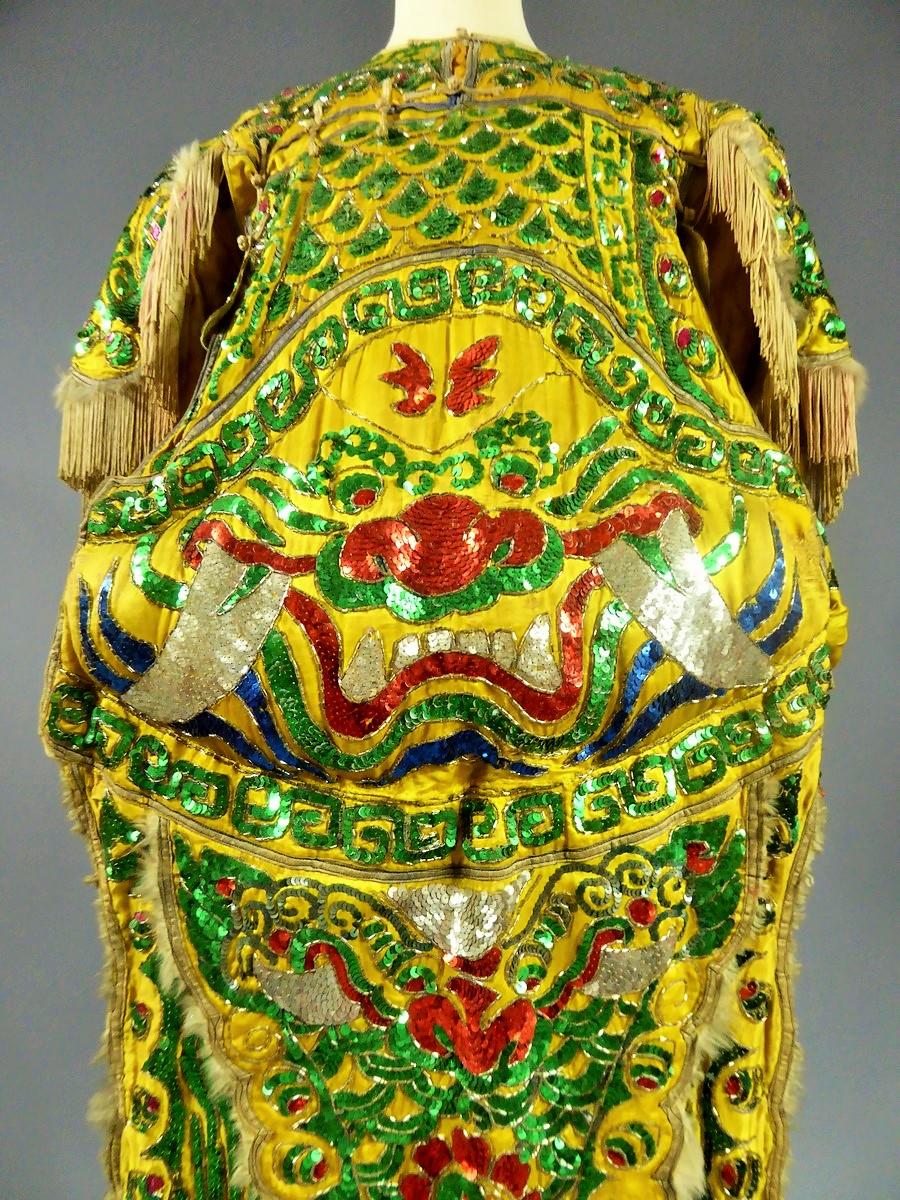 Circa 1900/1950

China

Artist's costume from the Beijing Opera, in imperial yellow satin cotton, embroideries of irregular sequins and tubular beads. The dress is tied by cotton bands on the lateral sides. On the padded ventral piece, a fantastic