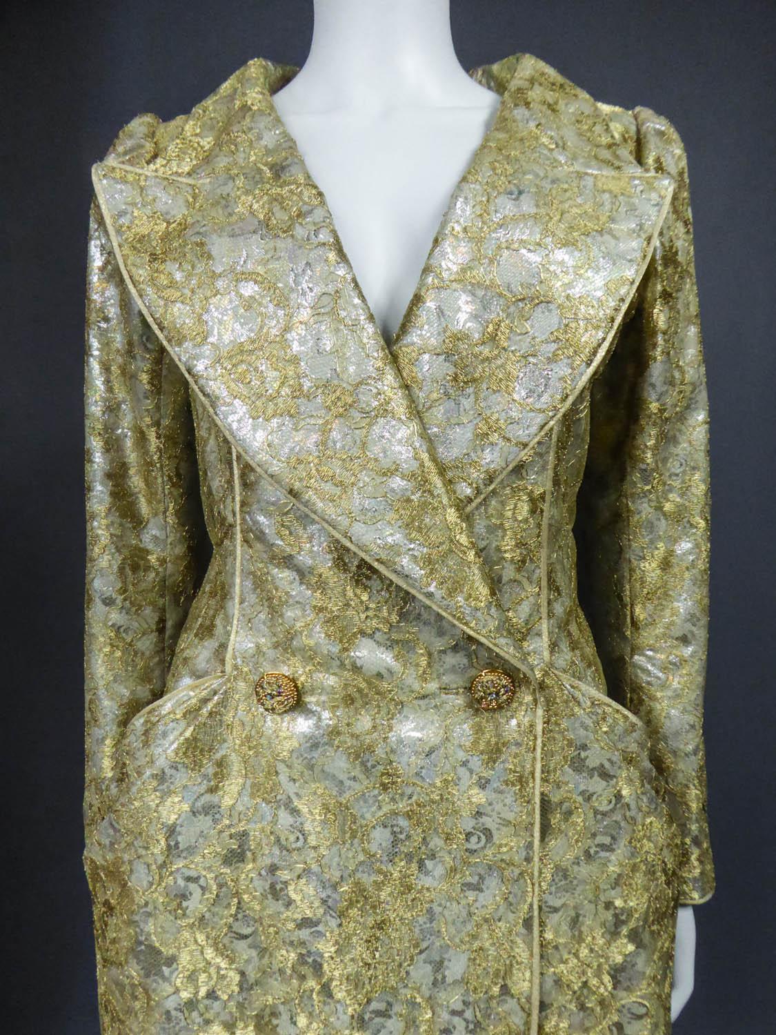Circa 1990
France

Haute Couture evening coat dress by Emanuel Ungaro from the 1990s. Silver lamé with floral patterns covered with gold lace overlay. Wide collar with plunging cleavage on the chest, hips marked by two side pockets with three