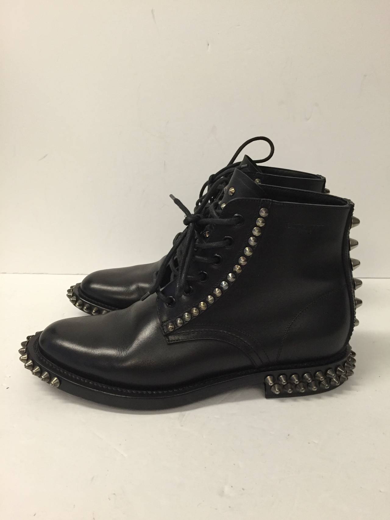 Ankle high leather boots in black. Round toe. Silver tone hardware. Cone spikes throughout. Black lace up closure with black eyelets. Embossed logo at collar. Paneled upper. Tonal stitching.

Size: 40

Worn twice!