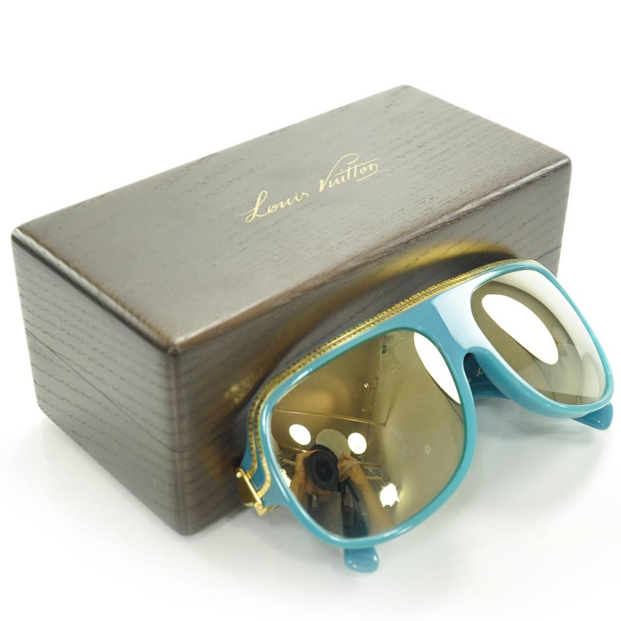 This is an authentic pair of LOUIS VUITTON Millionaire Sunglasses Turquoise w Gold Plated Lenses LE. These fabulous retro style sunglasses are turquoise with gold trim engraved with small Louis Vuitton LV logos. The large squared lenses have a tint