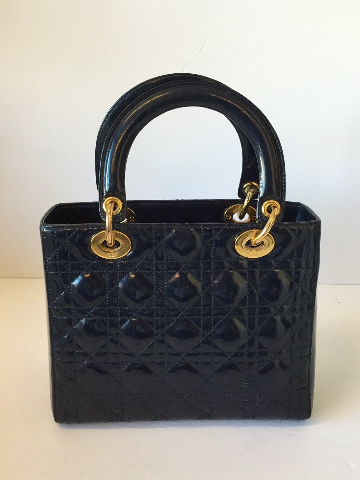 This structured bag is made of deep midnight blue patent leather with a quilted Cannage pattern embroidery. It features a dangling goldtone DIOR letter charms which adds some bling to this glamorous bag. This bag also comes with a removable shoulder