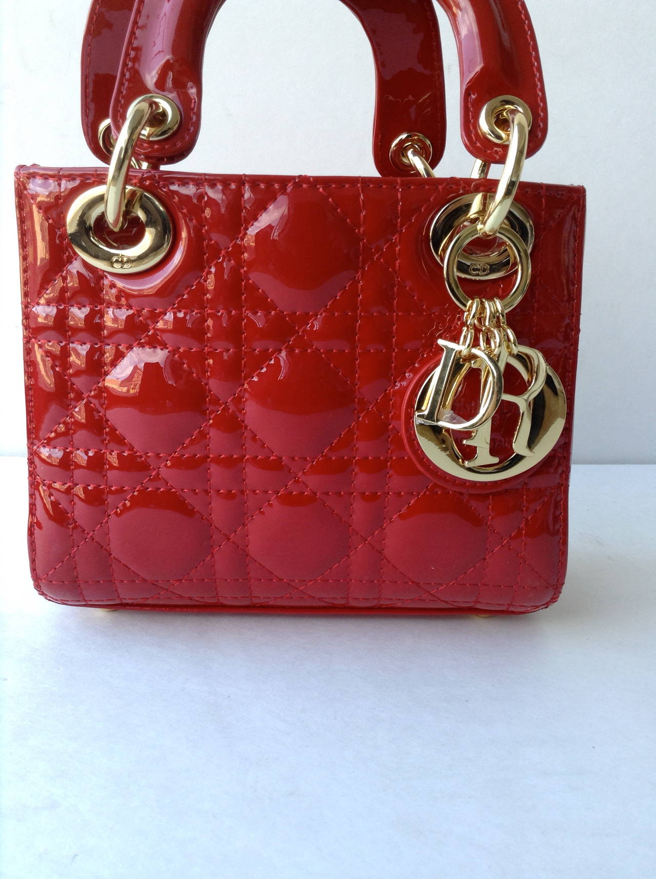 Authentic Christian Dior Lady Dior hand bag in red patent leather. Main access is secured with zipper. Inside has 1 zipper pocket and red fabric lining. Comfortably carried in hand or on shoulder with additional strap.

Made in: Italy

Size: 9.8