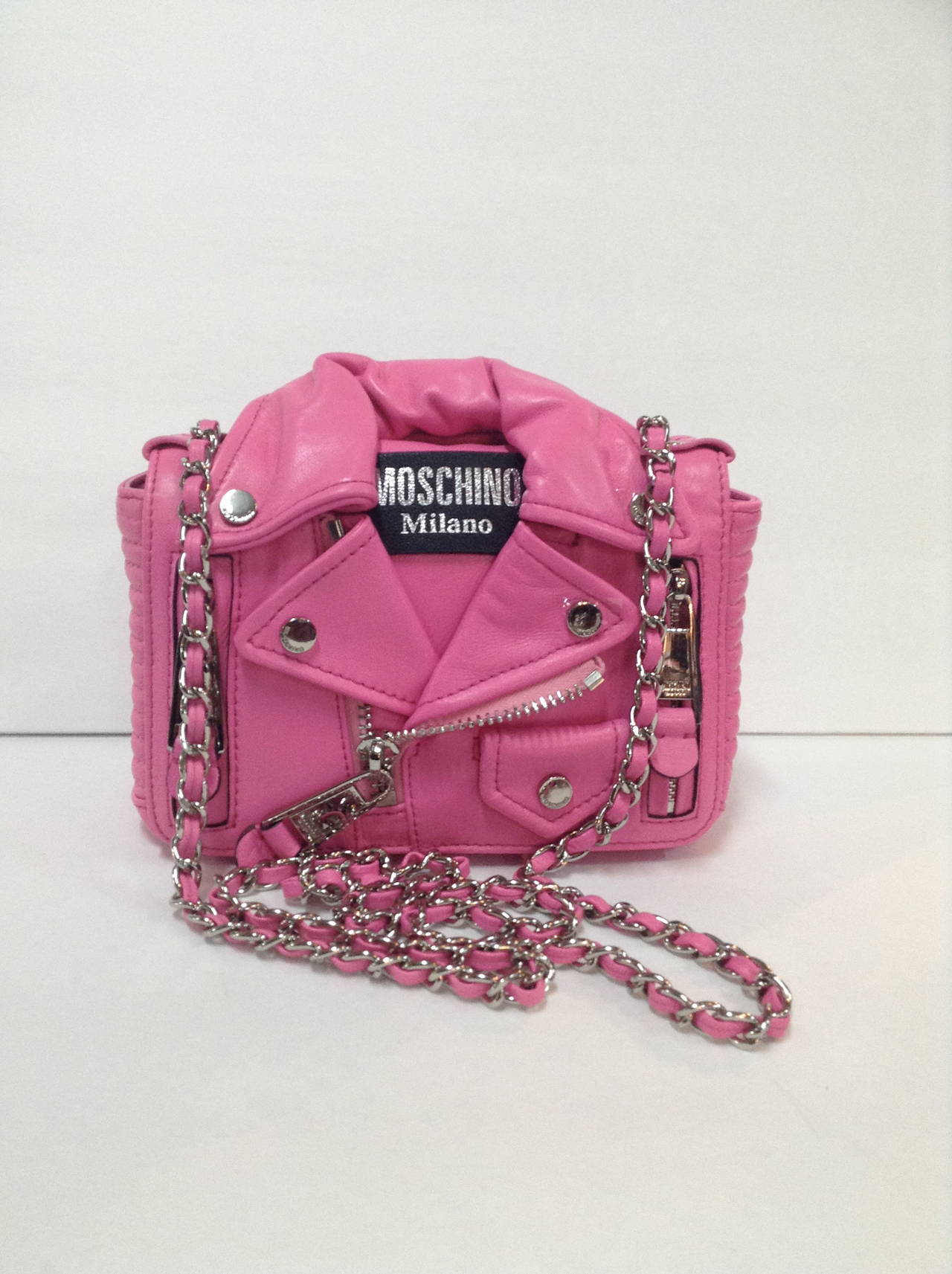 Authentic sold out 2014 Pink Moschino Mini Leather Biker Shoulder Bag. Adjustable metal chain and leather shoulder straps.

Front flap with snap button closure
Two front zip pockets
One internal leather patch pocket
Silver colored metal