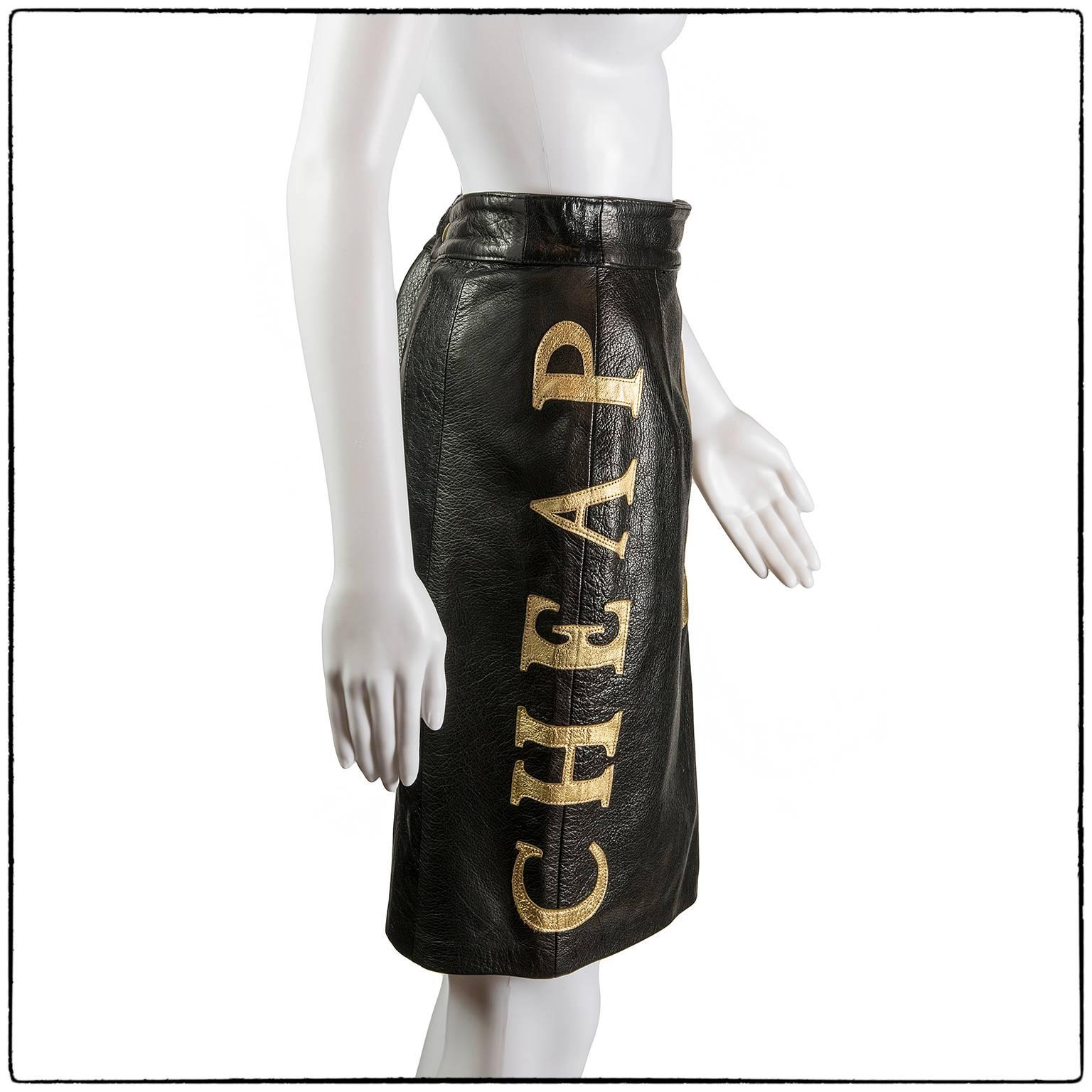 Rare and collectible black leather skirt by Moschino featuring the words “Cheap & Chic” in huge gold lettering, 1990s
This leather skirt has “Cheap & Chic” written all over it in gold leather
Also features a button/zip closure at back and
