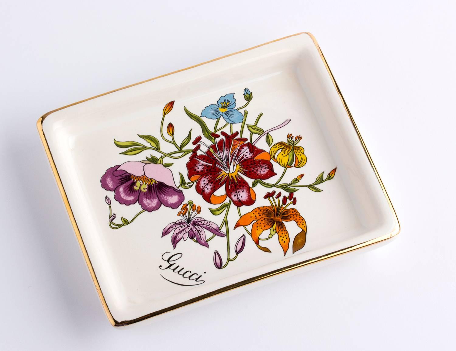 - White Porcelain
- Gold detailing along the borders
- Flora theme design in the center
- 'GUCCI - Made in England' embossed on the base of the ashtray
- Rectangular-Shaped
- MEASUREMENTS : 13,5 x 10,5 cm

Condition: GOOD CONDITION - Used once or