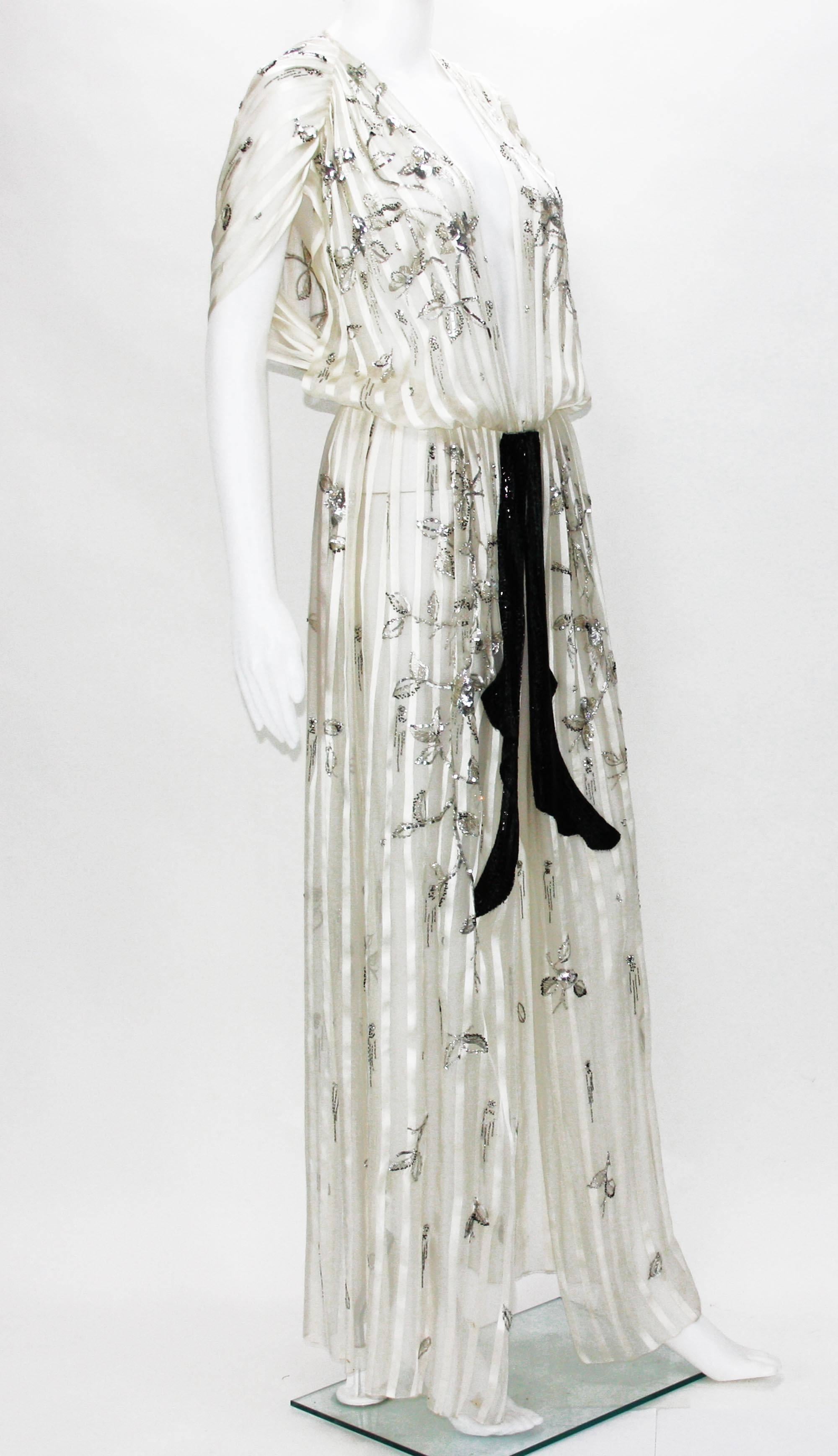 Christian Dior Paris 
Embellished Dress Duster
Printemps-Ete 1979
Numbered - 011612
Color - Ecru.
Finest Silk Sheer.
Embroidered birds, butterflies and flowers with Silver tone Sequins and Black Little Beads.
Fully Beaded Belt-like.
Hook and eye