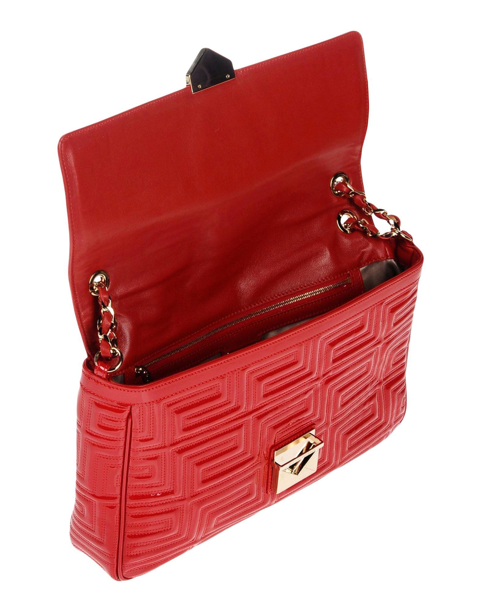 This designer shoulder bag from Versace features an allover stitched quilt pattern on red patent leather. A gold tone chain and matte leather shoulder strap combines with a push-release lock closure to complete this bag with functional style.