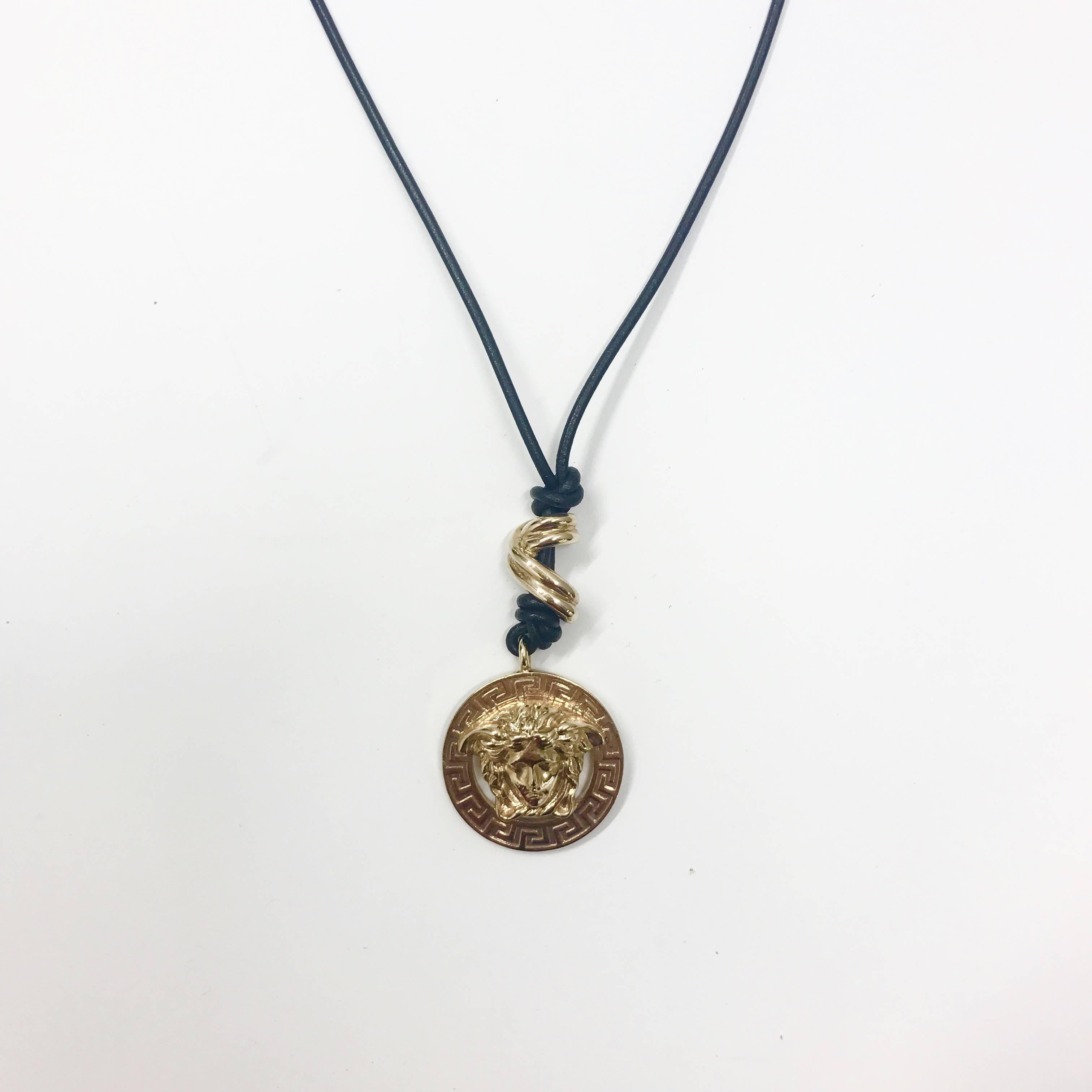 The classic medusa Versace gold tone metal pendant. The knotted leather strap is inspired by the sun drenched and rustic beach culture of Gianni’s costal home region of Calabria. the medallion itself is engraved with his iconic greek titling motif