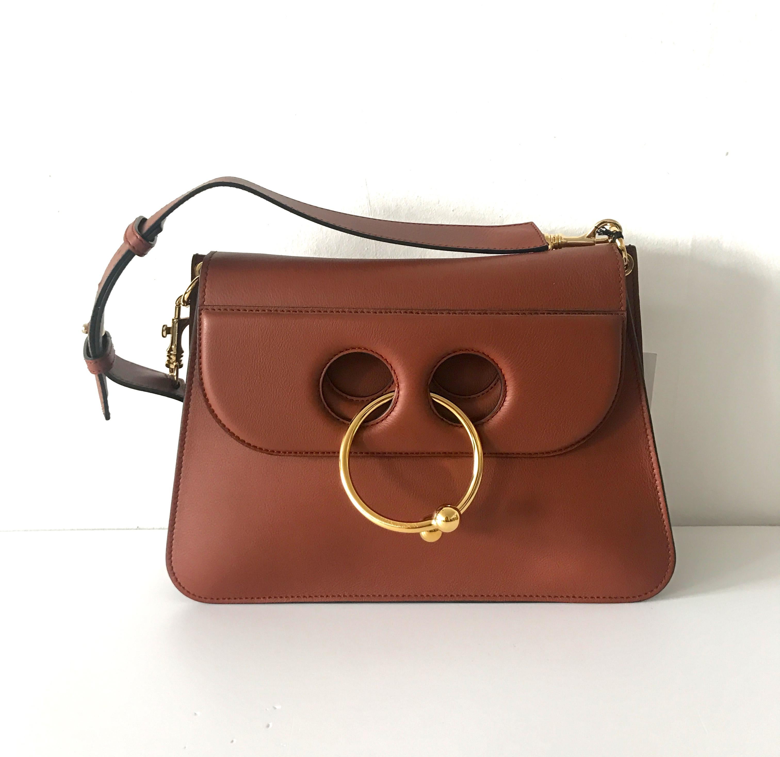 J.W.Anderson's Pierce medium shoulder bag is crafted of brown supple calf leather. Designed to resemble a septum piercing, this playful style is embellished with a goldtone metal double-ball ring that 
