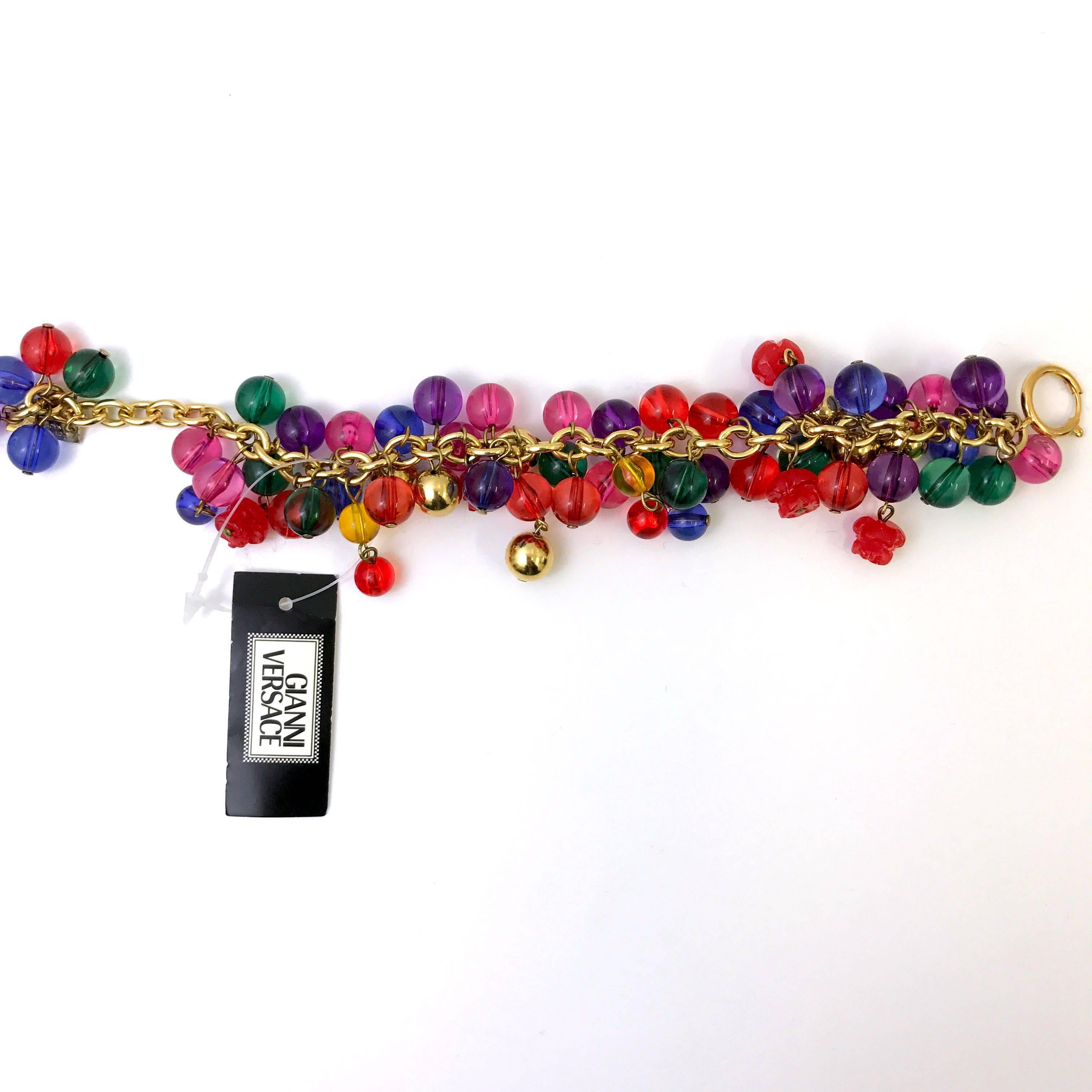 This bracelet features a multicoloured cluster of vibrant glass beads. The designer Gianni Versace captures his iconic colourful designs in this piece. Each coloured bead is hanging from the gilded gold tone metal chain. Stamped with his Gianni