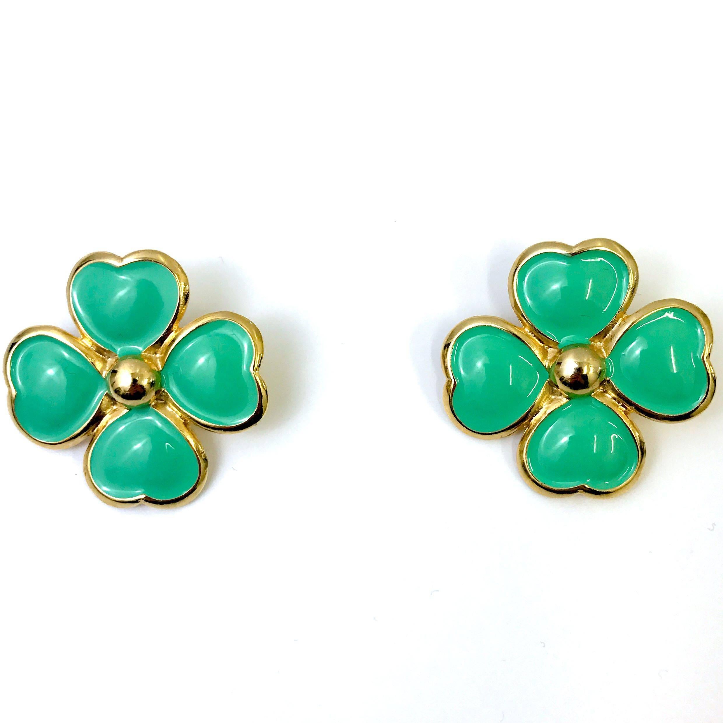 These flower clip on earrings by Gianni Versace feature a gold tone metal base. The real highlight of the piece is the light green enamel colouring which lifts any outfit. Finished with Gianni Versace made in italy stamp.