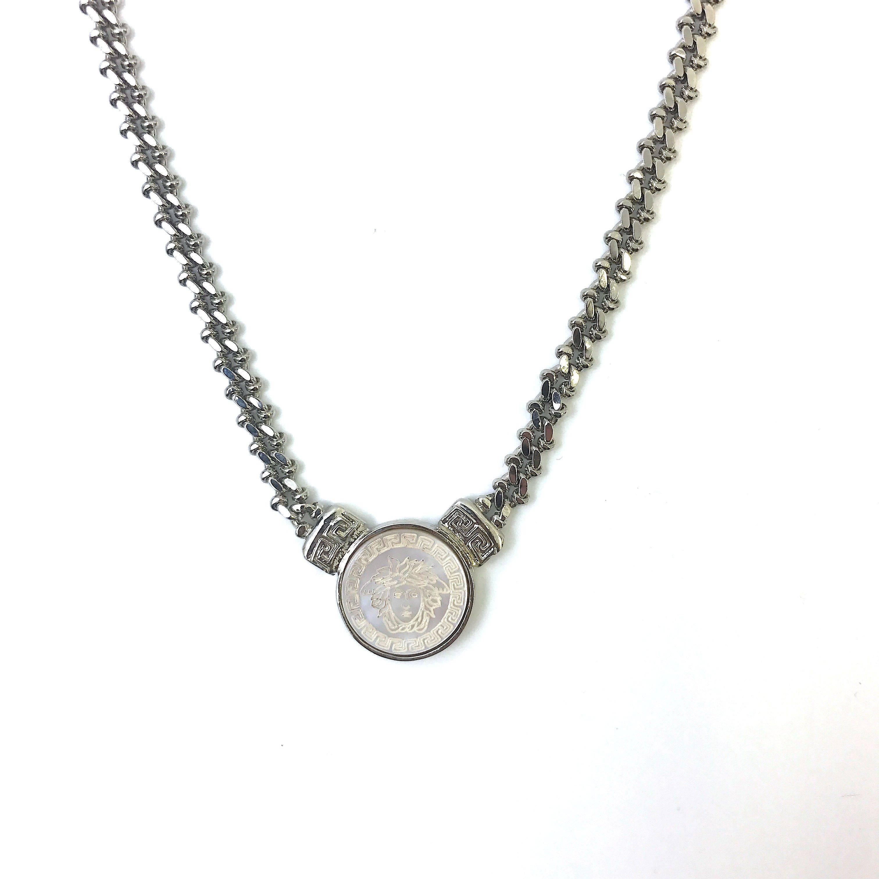 A very rare and timeless piece from the 1990's by designer Gianni Versace. The piece features a very unique curb style chain in a stunning silver toned metal. It is beautifully finished off with a detailed engraved medusa head on a mother of pearl