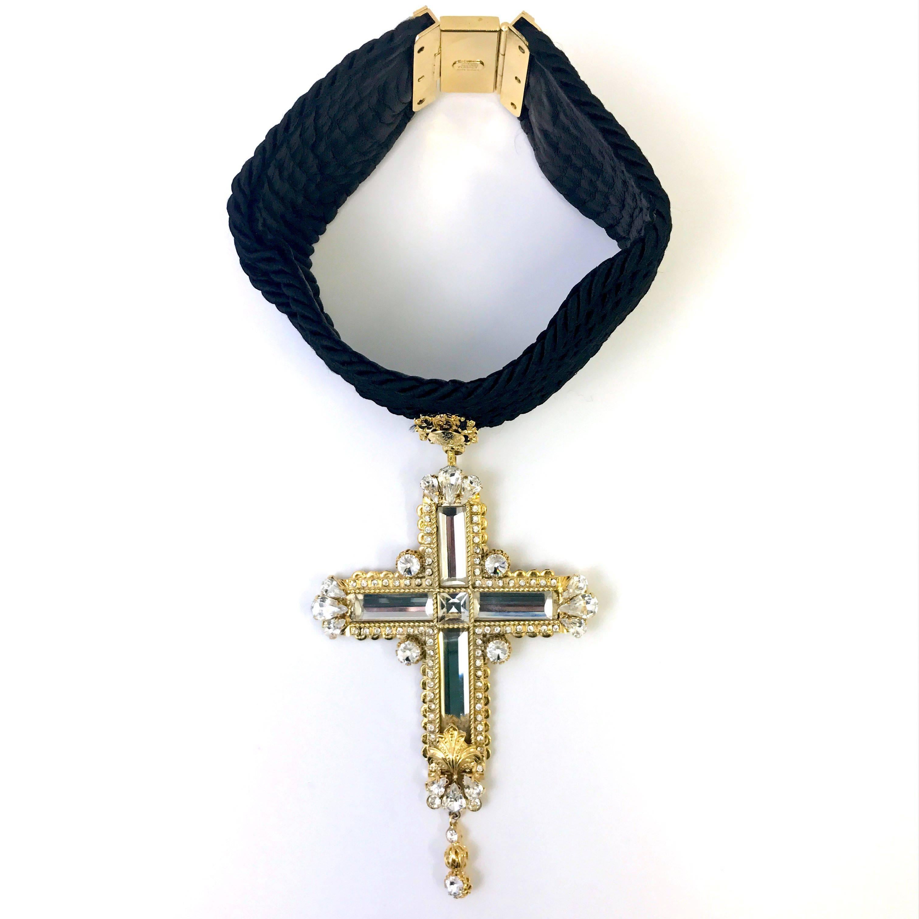 This is an extremely beautiful and rare statement choker from Gianni Versace. The handcrafted piece features a thick rope choker with a stunning and intricately made cross pendent dropping from the choker. The gold tone cross and rhinestone accents