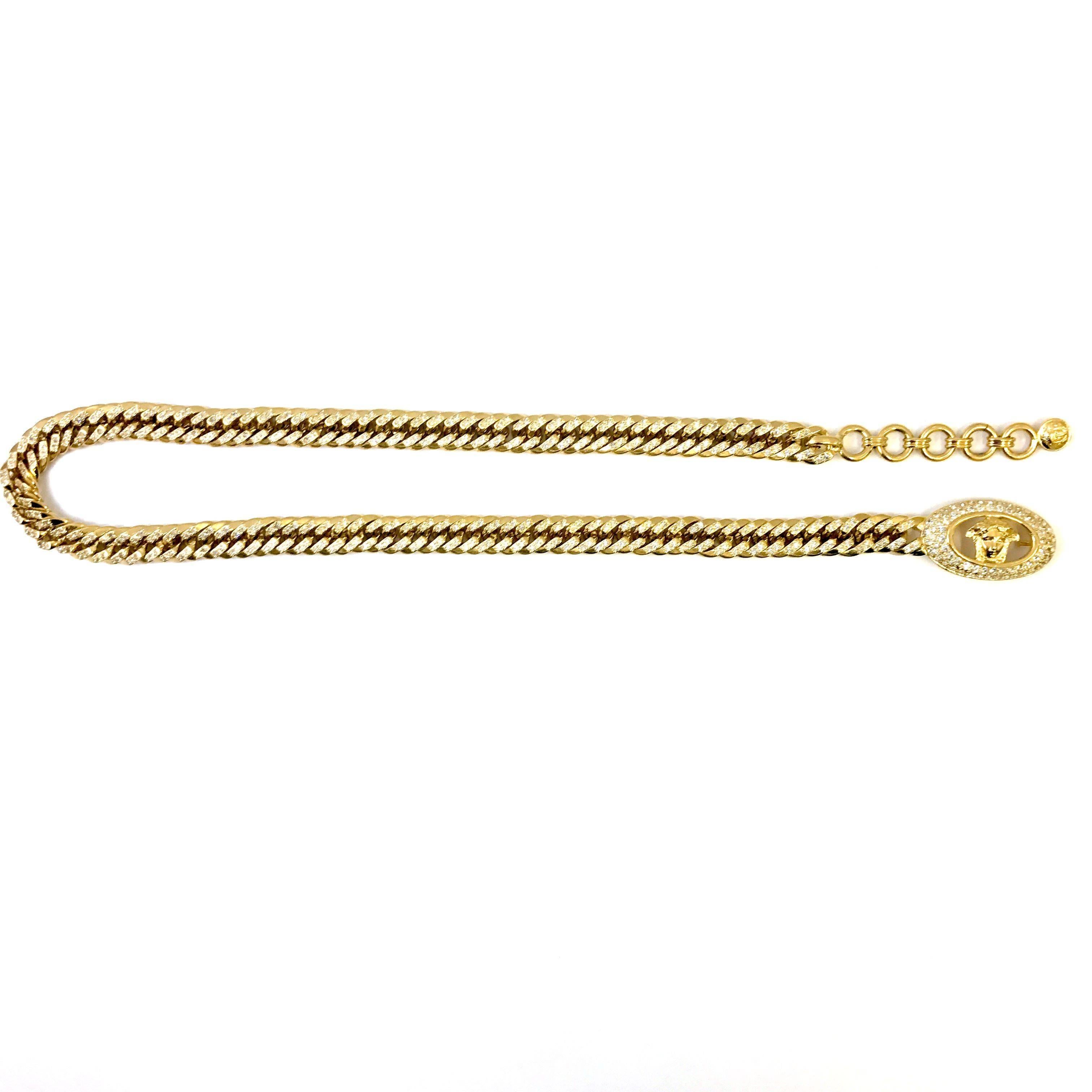 Dieser Gianni Versace Gürtel ist aus goldfarbenem, vergoldetem Metall gefertigt. Der Stil der Kette spiegelt die Ära der 90er Jahre wider, denn sie hat die Form einer Panzerkette. Die Kette des Gürtels ist mit klaren Strasssteinen besetzt, die
