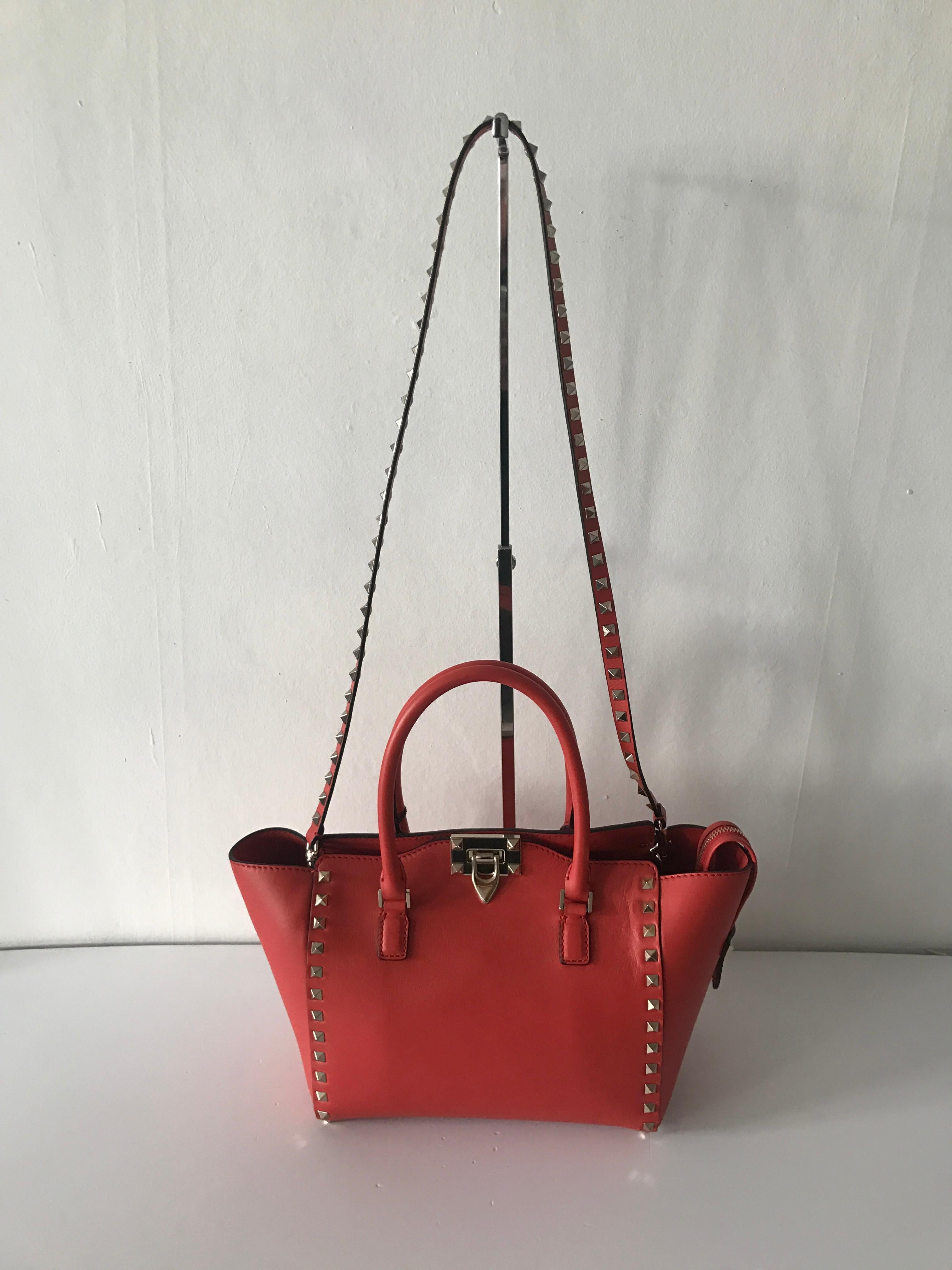 This Rockstud Small Double Handle tote from Valentino perfectly blends Italian elegance with contemporary detailing. This handbag is a bold statement in the cherry red colour. The Rockstud Small Double Handle toe features round top handles, a