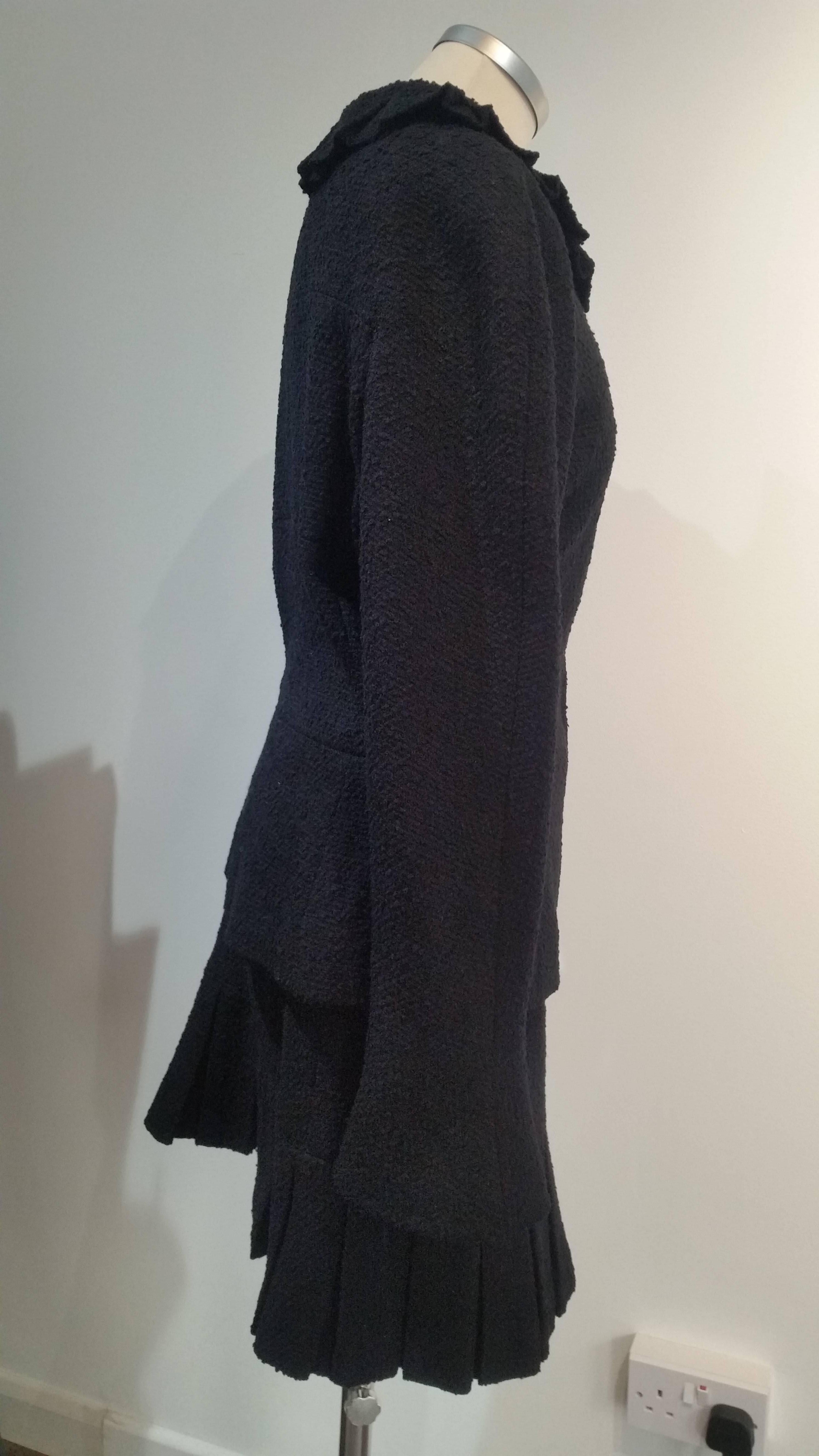 Vintage Chanel Black Boucle Skirt Suit. Nipped in waist
Season: 97 A
Silk lining with Double C.
Chain stitched into hem.
Chanel button on one of the sleeves
Completely lined.
Zip up front.
Ruffle neckline with Chanel  zipper fastening.

Skirt has