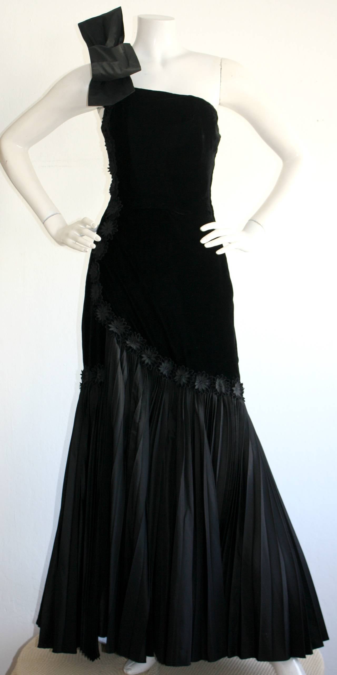 Stunning vintage 1940s black silk velvet one shoulder gown, with bow at top shoulder. Intricate black flower embroidery throughout. Beautiful asymmetrical accordion hemline, that makes for dramatic movement. A true beauty of a gown! In great