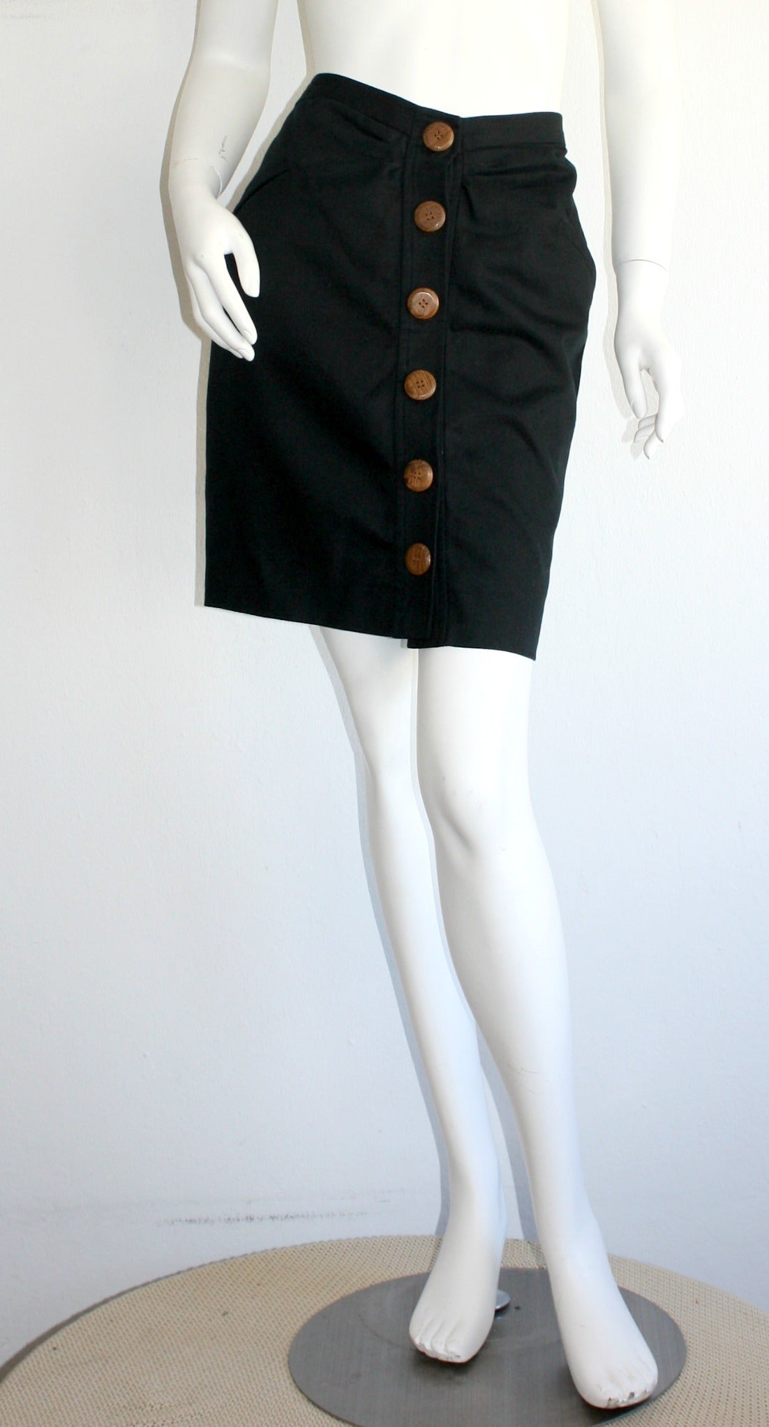 Beautiful classic black YSL skirt, with a twist! Functional oversized wood buttons down the front. The perfect little black skirt. In great condition. Marked Size 42

Measurements:
30 inch waist
40 inch hips
19 inches in length
