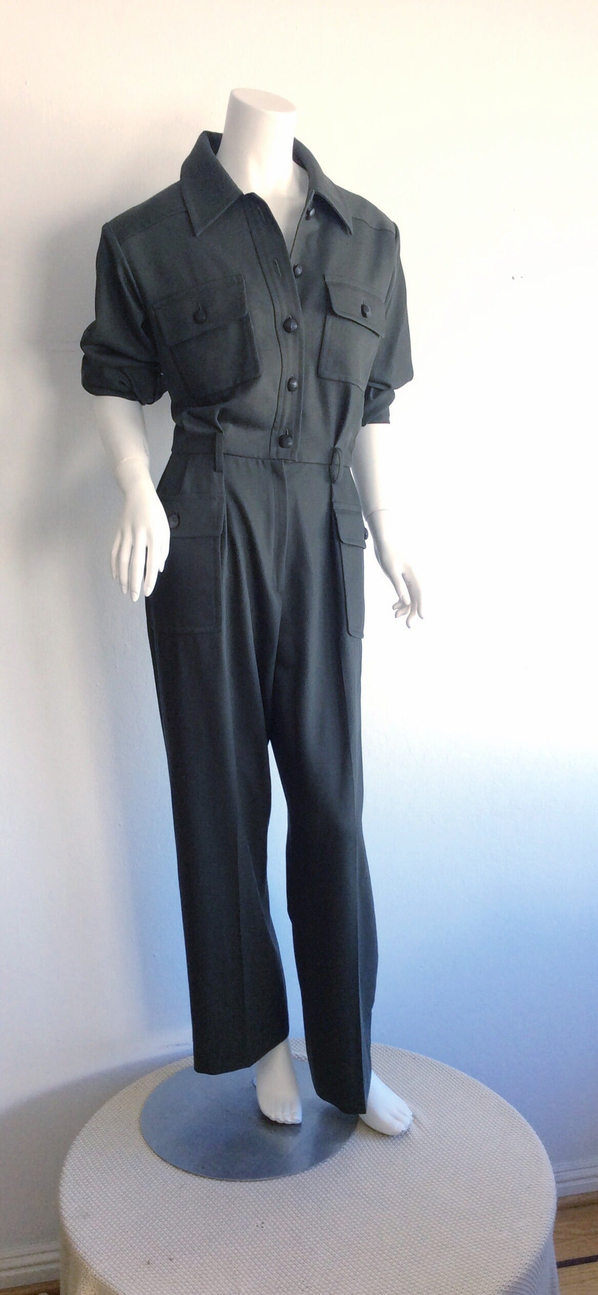 Extremely chic, and iconic vintage YSL army green jumpsuit! Impeccable tailoring, featuring buttons up the bodice, with signature YSL lapels. Pleated pants, with belt loops to add your favorite belt. Buttons at each cuff. Also looks great with