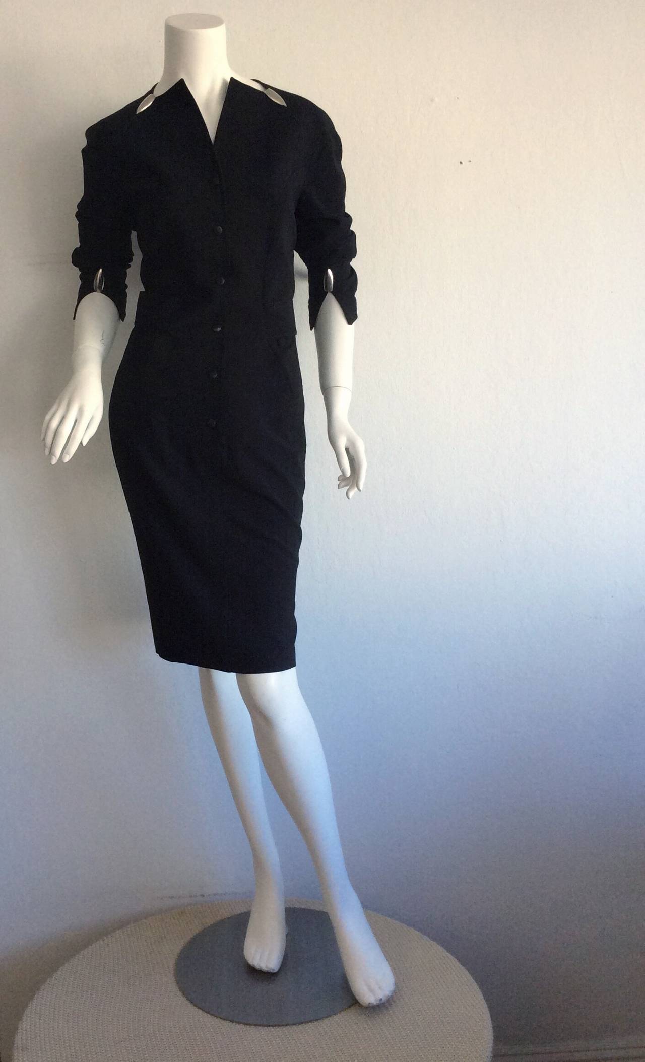 Remarkable vintage Thierry Mugler black dress! Features silver metal 'bullets' at collar, cuffs, and on one side of the skirt hem (at slit). Attached belt that fastens in the back, with the signature angled Mugler buckle. Snaps shut up the bodice,