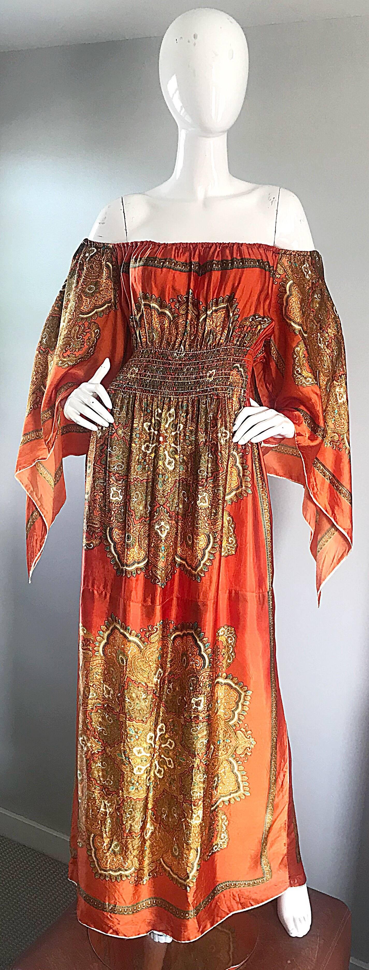 Amazing 1970s off-the-shoulder brightly colored orange handkerchief maxi dress! Features an orange background, with yellow, green, and blue ethnic prints throughout. Dramatic scarf sleeves look fantastic on! Can also be worn on the shoulders (see