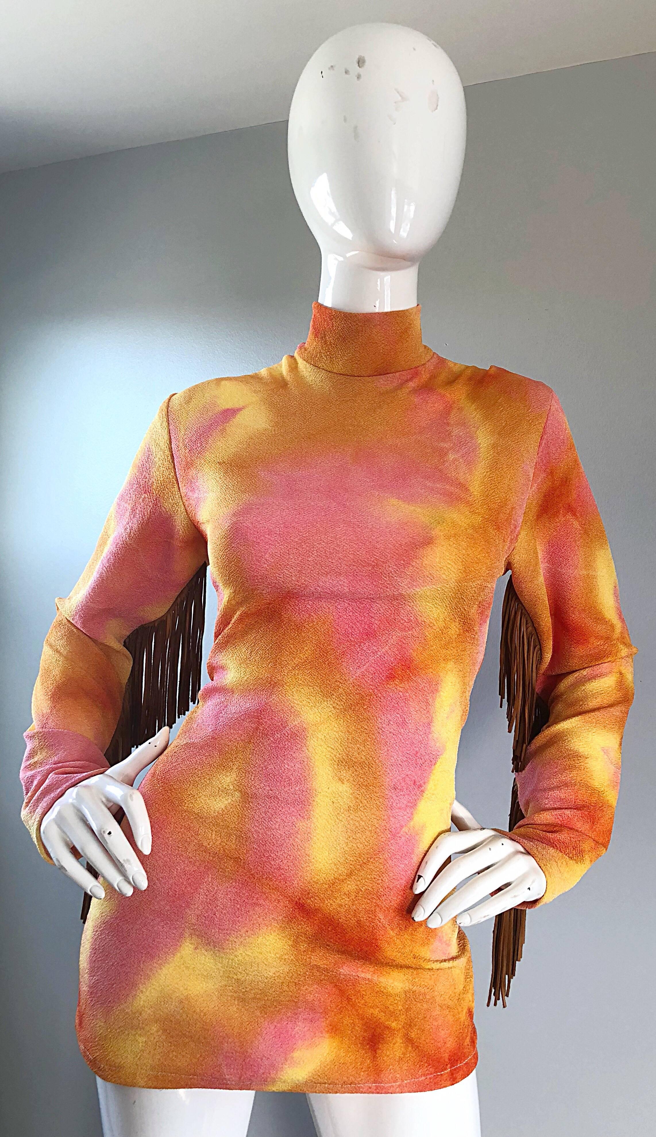 Amazing vintage 70s pink and orange tie dye tunic top! Features a flattering stretch to fit silhouette, with a high mock neck. Brown / tan leather suede fringe on the back of each sleeve. Great belted or alone, and can easily be dressed up or down.
