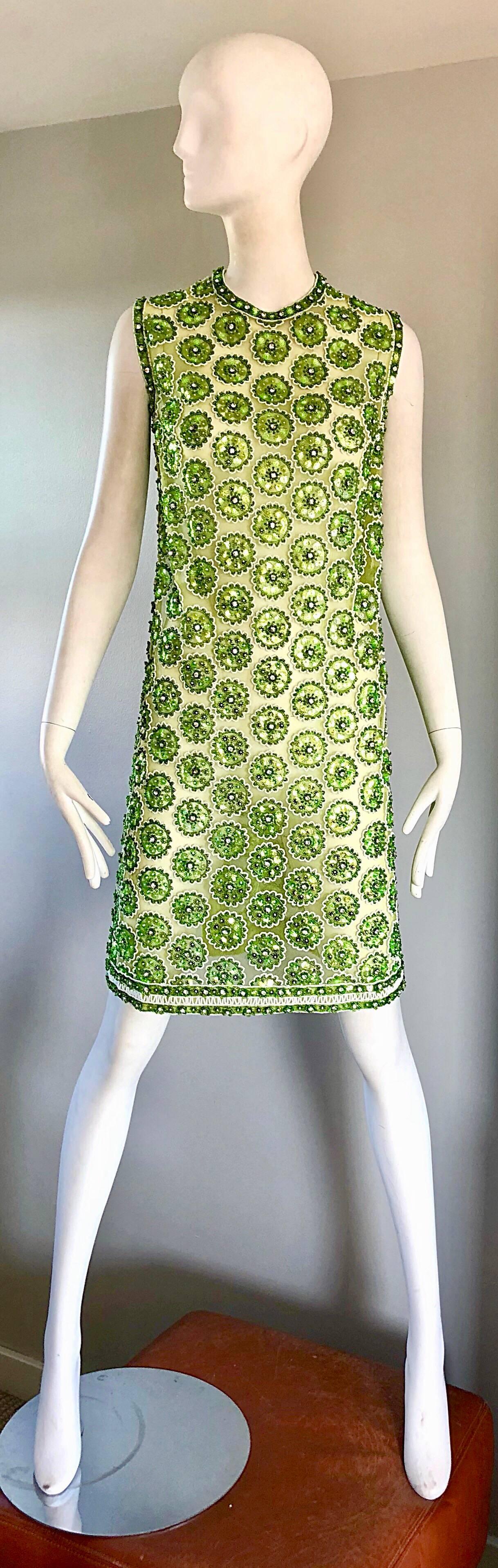Chic 1960s fully sequined and beaded mesh demi couture tunic dress! Features thousands of hand-sewn sequins, rhinestones, and beads throughout to form flower shapes. Full metal zipper up the back with hook-and-eye closure. Semi sheer net mesh. High