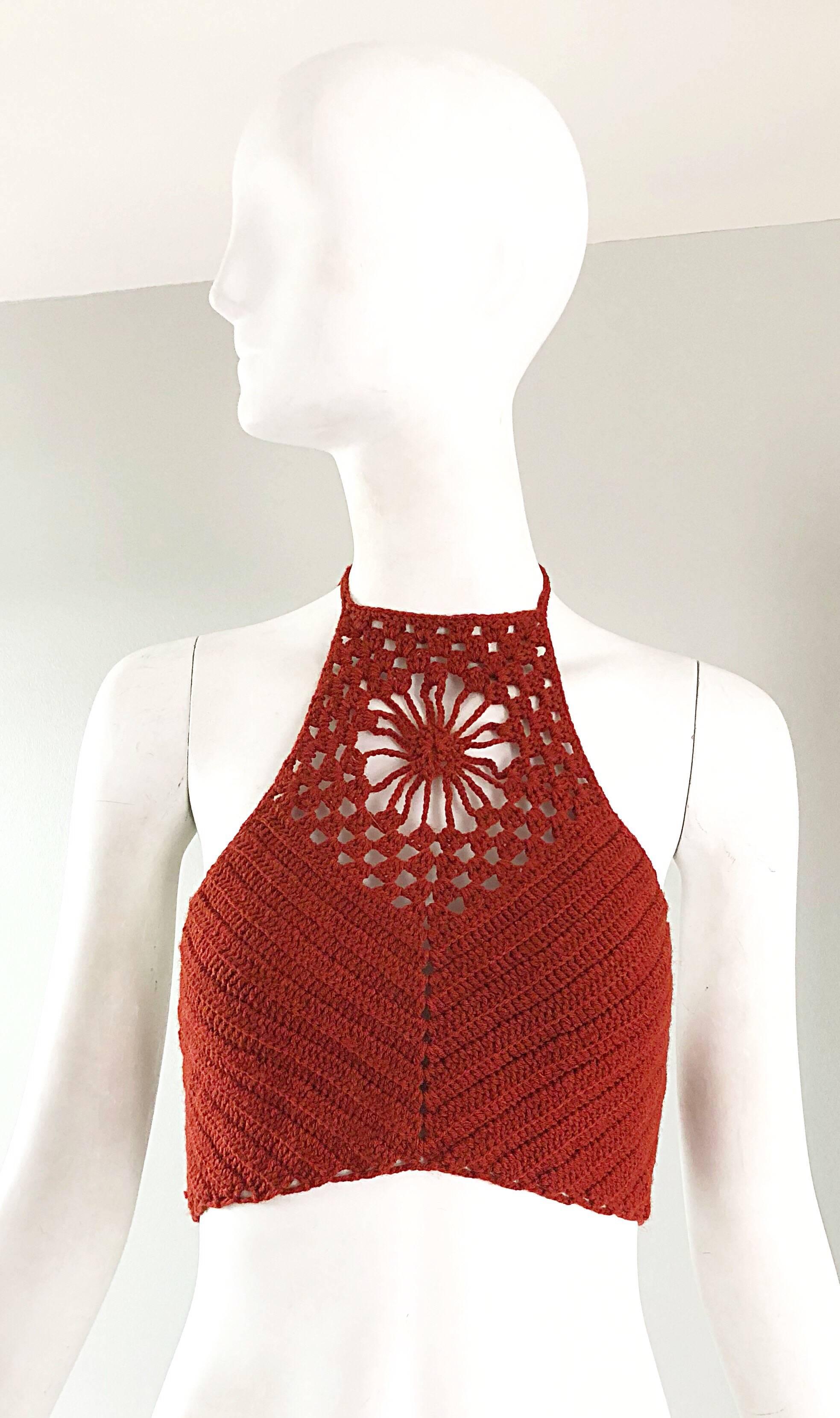 Sexy 1970s hand crochet woven burnt orange halter crop top! Features a woven flower above the center bust. Ties at the back, and at back neck. Great with shorts, jeans or a skirt. In great unworn condition. 
Approximately Size Extra Small - Medium