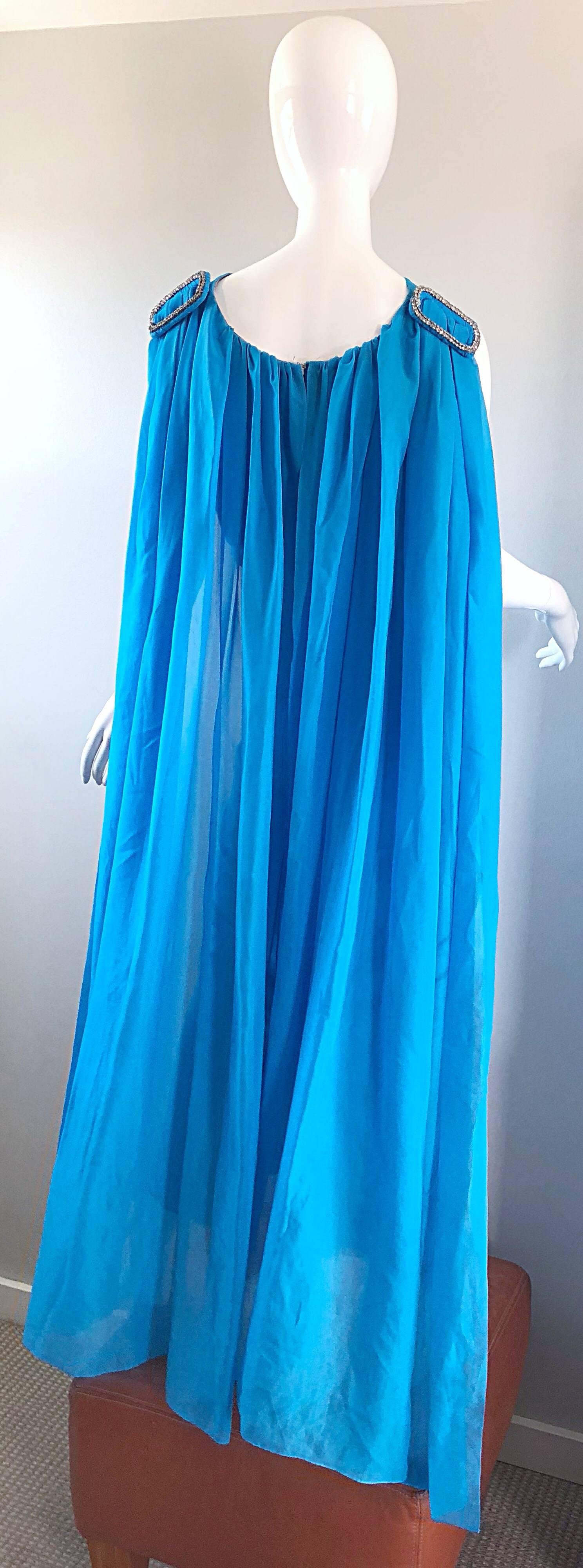 Incredible late 60s turquoise blue chiffon rhinestone encrusted gown with attached cape! Wonderful tailored fit with a fitted bodice and skirt. Attached semi sheer chiffon cape features a large rhinestone encrusted buckle on each back shoulder.