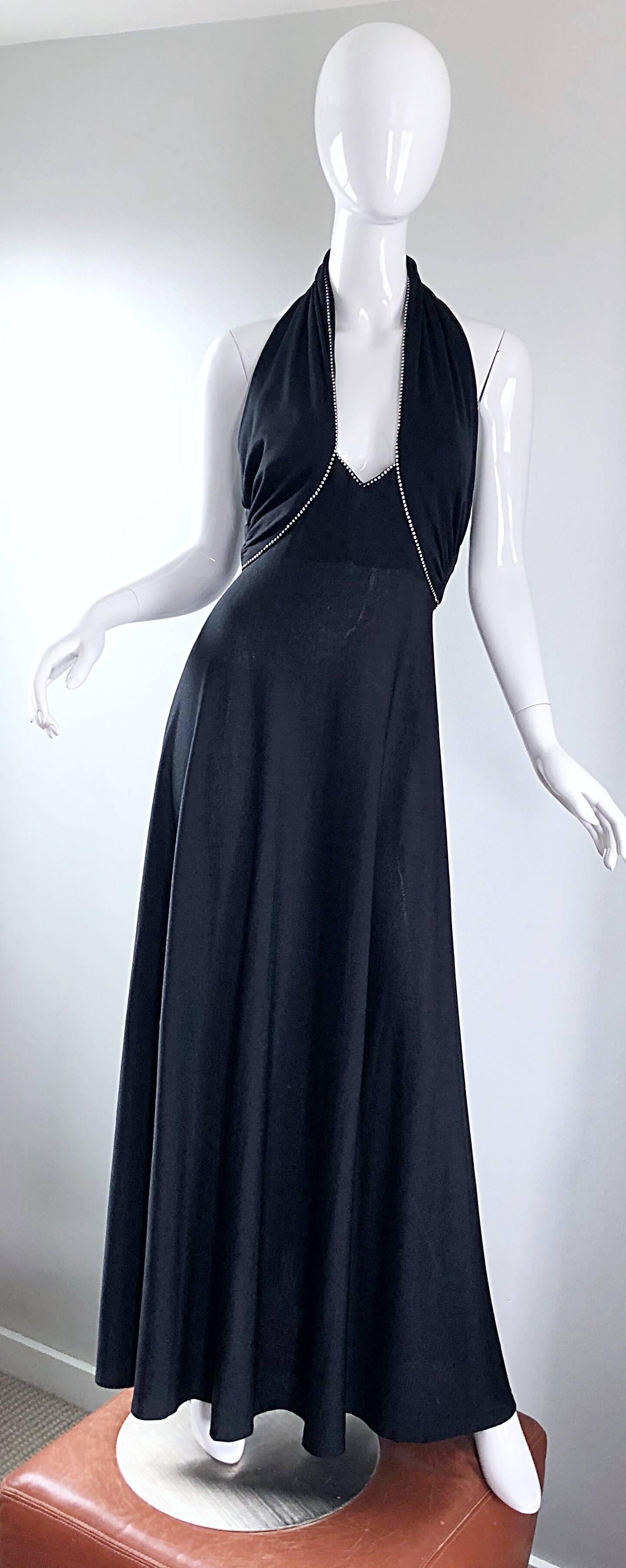 Sexy 1970s black jersey rhinestone encrusted Grecian inspired full length evening dress! Features a plunging neckline with panels at each side of the breast that button shut at top back center neck. Hidden zipper up the back. Lots of attention to