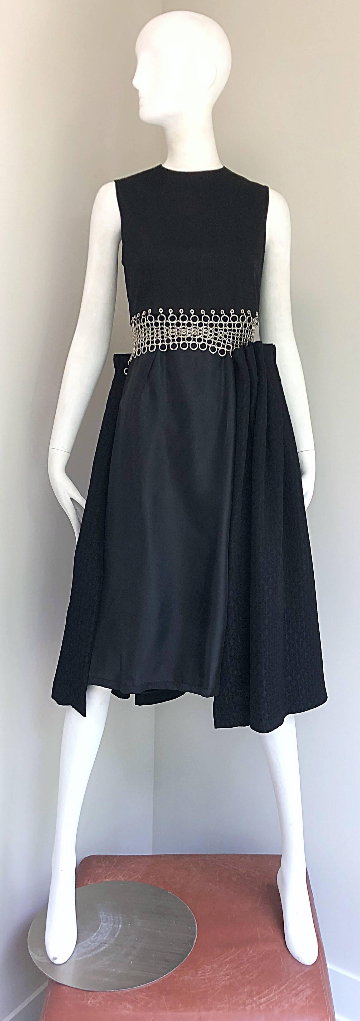Rare Limited Edition brand new with tags COMME DES GARCONS NOIR KEI NINOMIYA black sleeveless Avant Garde cotton dress! Features a tailored bodice with an asymmetrical slight A-Line skirt. Hundreds of hand-sewn silver metal grommets adorn the front