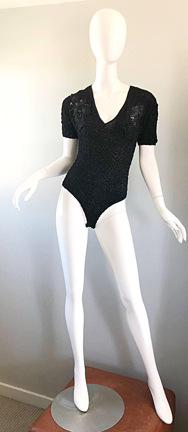 Sexy 1990s black French sequined and beaded short sleeve peek-a-boo one piece bodysuit! Features a soft fabric that stretches to fit. Peek-a-boo details at shoulders are encrusted with black sequins and beads with appliqués. Great with jeans,