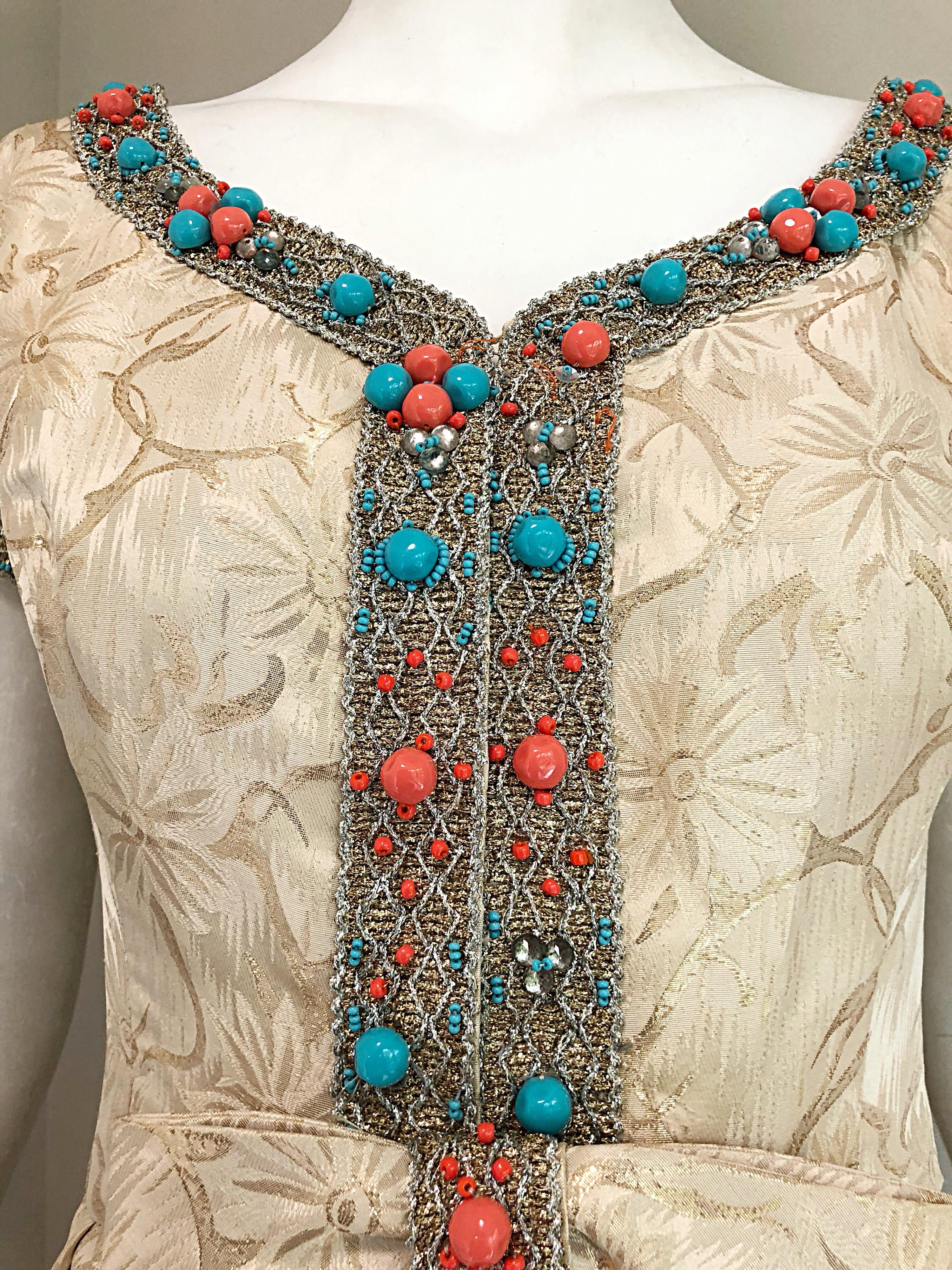 Beautiful 60s light gold silk turquoise blue and coral beaded evening gown! Features a fitted bodice with hundreds of 
hand-sewn coral / salmon and turquoise beads of various sizes around the neck and at each sleeve cuff. Luxurious pale gold silk