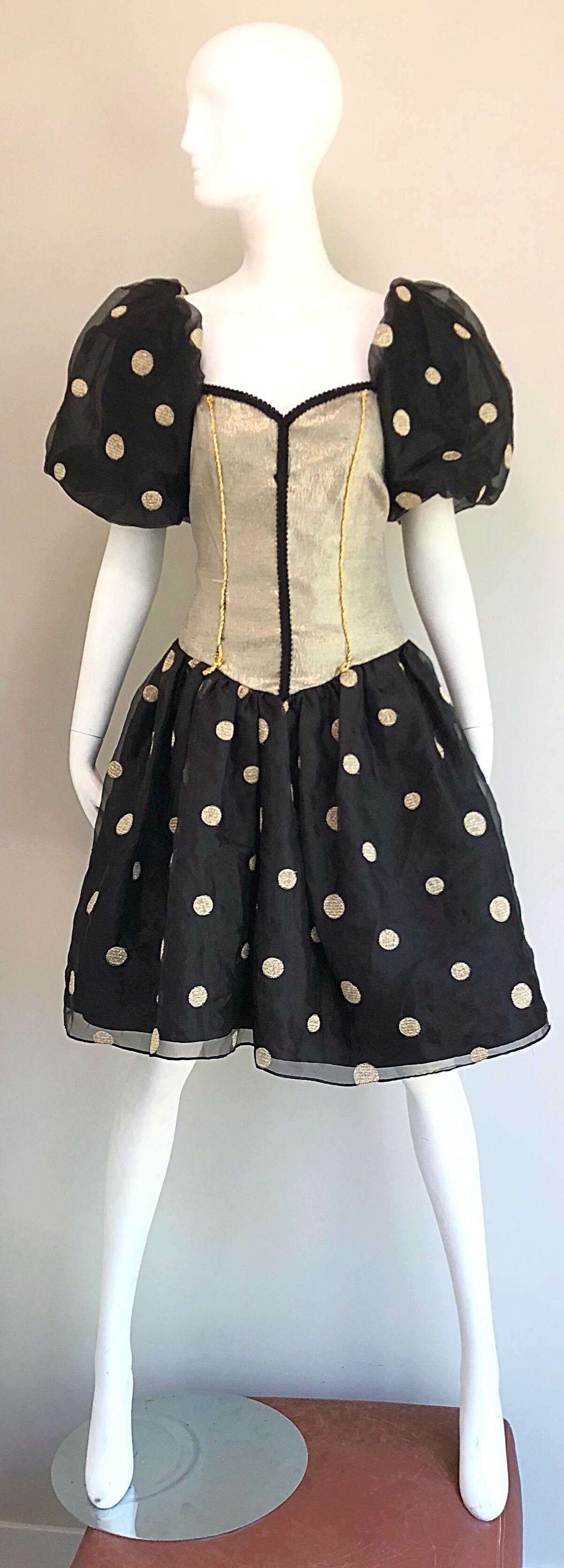 Fabulous Avant Garde 1980s gold and black polka dot fit n' flare corset cocktail dress! Features a muted gold nipped bustier type bodice with oversized chiffon puff sleeves. Flirty full skirt. Hidden zipper up the back with hook-and-eye closure.