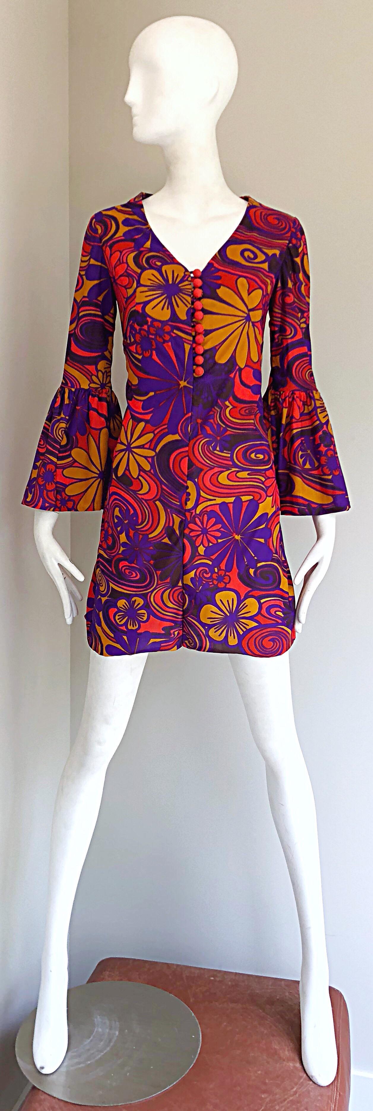 Amazing early 1970s flower power psychedelic tunic mini dress! Features flowers in various sizes, mixed with psychedelic prints. Vibrant colors of purple, orange and red throughout. Mock buttons up the bodice. Hidden zipper up the back. Great alone,
