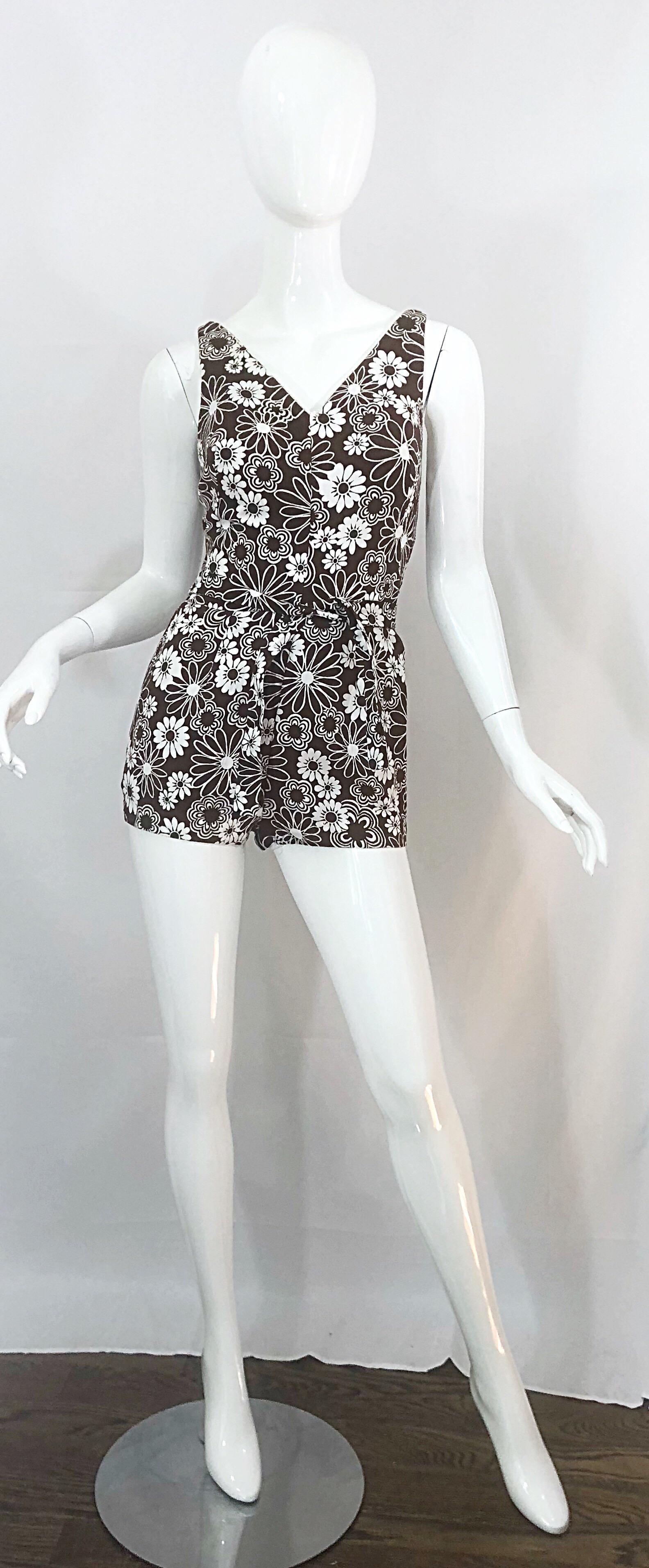 Chic 1960s brown and white flower print one piece belted romper swimsuit! Features white and brown daisy flowers printed throughout. Belt ties at side waist. Adjustable buttons at each top strap to adjust for size / height. The perfect timeless