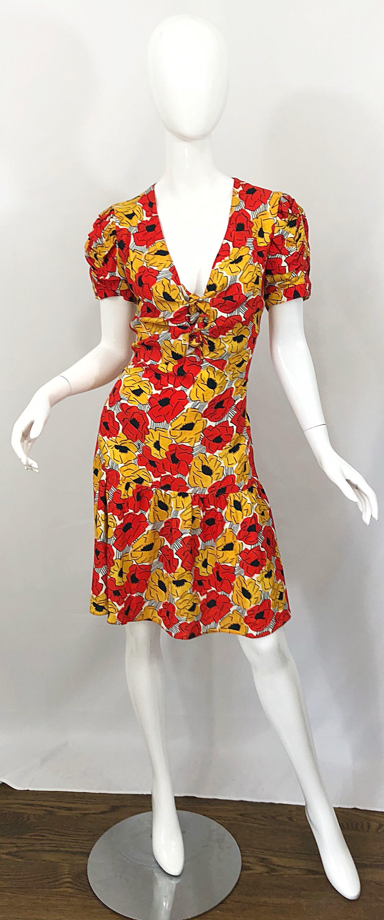 Beautiful YVES SAINT LAURENT red, yellow, black and white poppy print drop waist cut-out dress! Features vibrant colors of red and yellow with black and white throughout. Subtle cut-out details at center bust with ties. Hidden zipper up the side.