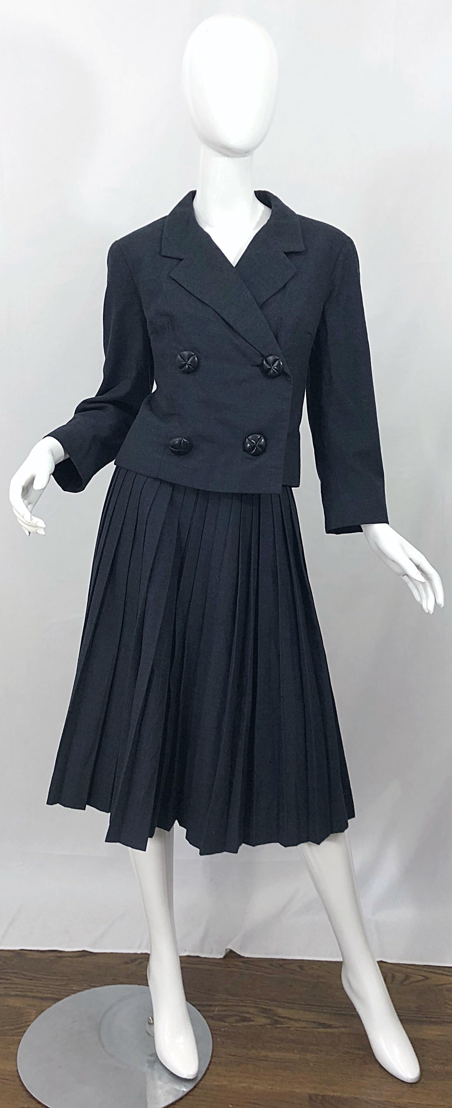 Chic, classic and rare early 1960s CHRISTIAN DIOR demi couture charcoal gray  wool skirt suit! Features a pillbox style cropped double breasted jacket, and knife pleated skirt. Large black lacquer carved buttons, with hidden snap closures. Skirt has