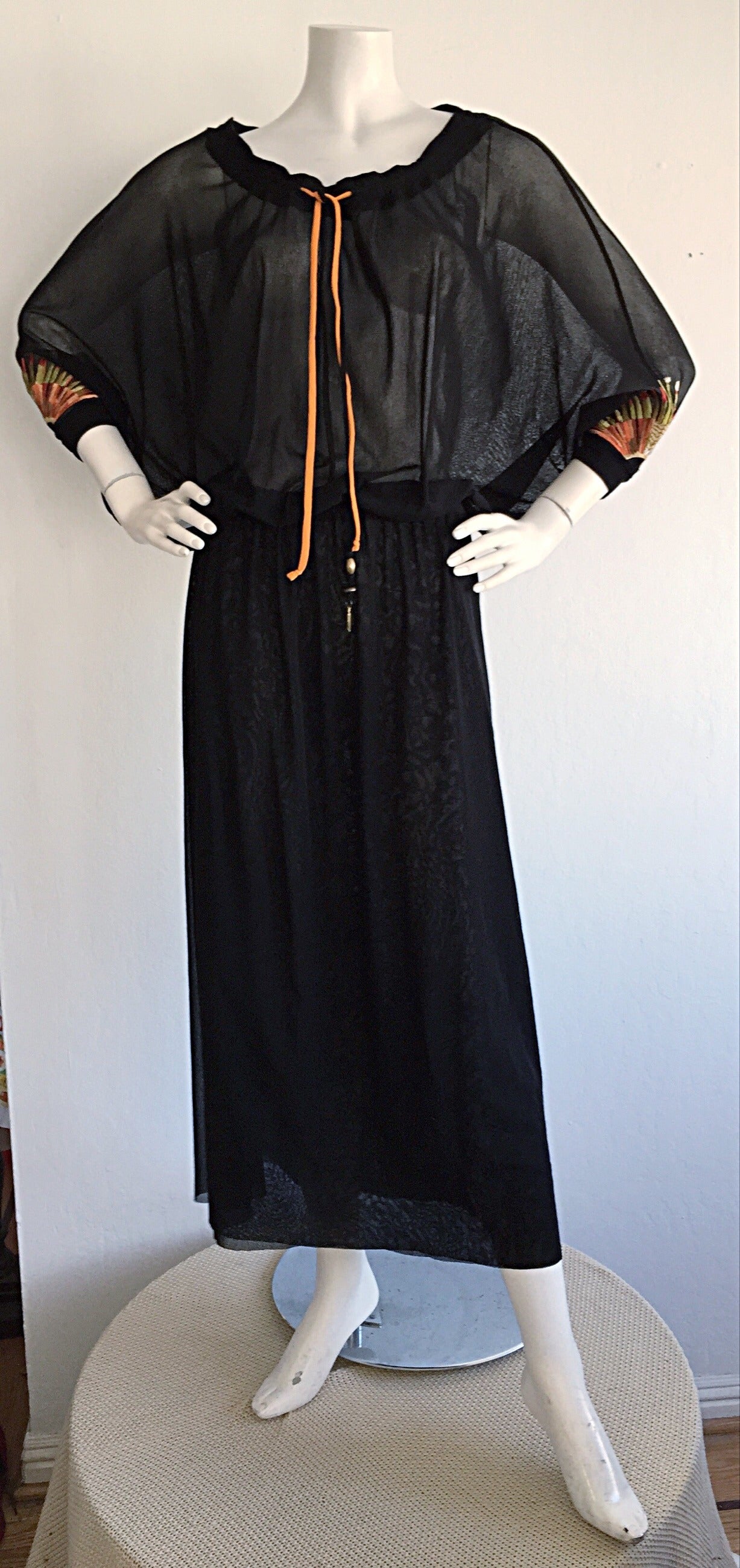 Incredible 1990s Vintage Jean Paul Gaultier caftan! Signature black double layered nylon mesh, with drawstring neck. Two silk drawstrings of orange and black, with decorative charms, can be let loose, or tied for a tighter fit. Embroidered sunbursts