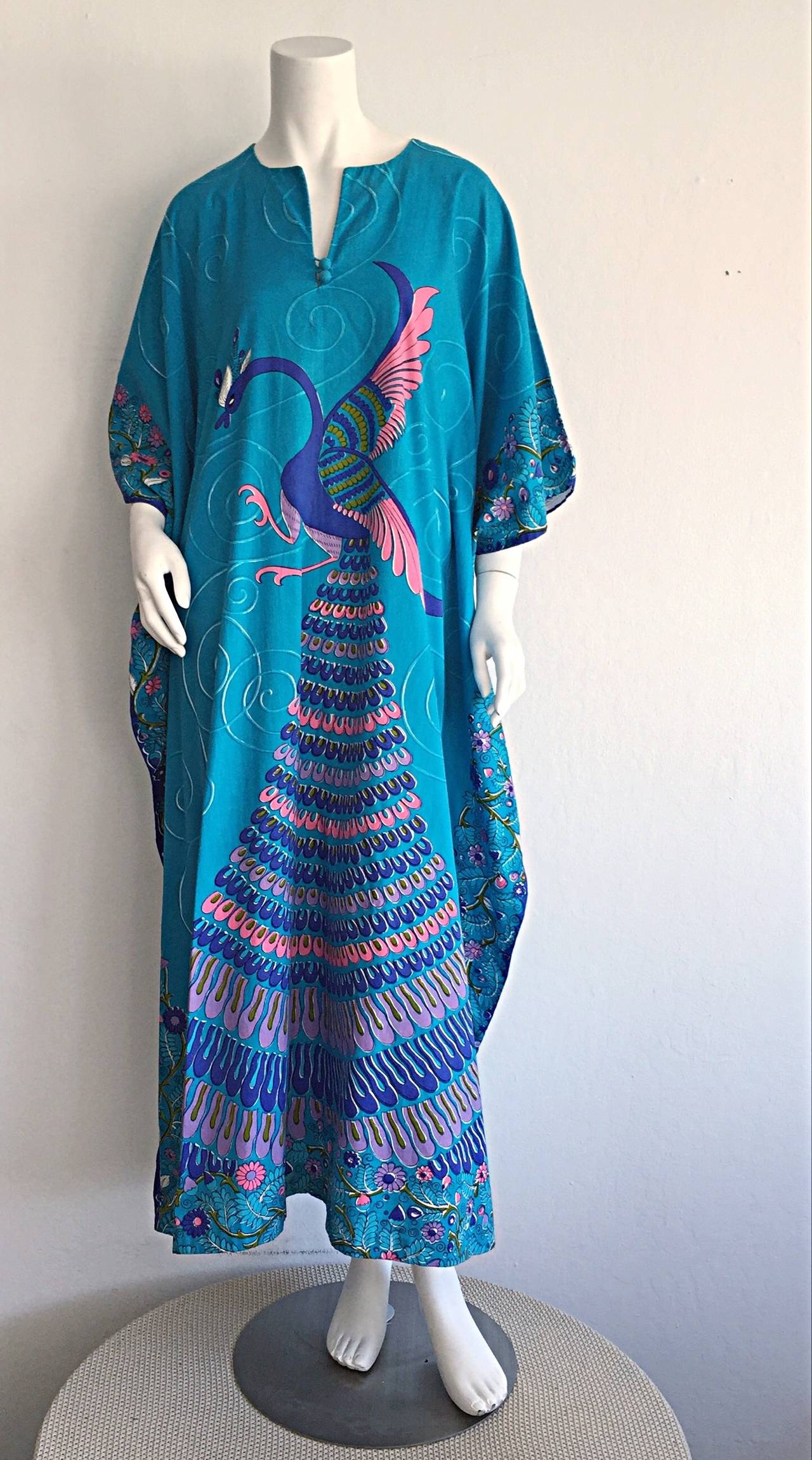 Incredible vintage Neiman Marcus Peacock cotton caftan. Vibrant blue, with colorful print throughout. Buttons at bust. A true caftan that is a rare gem! Looks great alone, or belted. Perfect over a swimsuit. In great condition. Will fit most