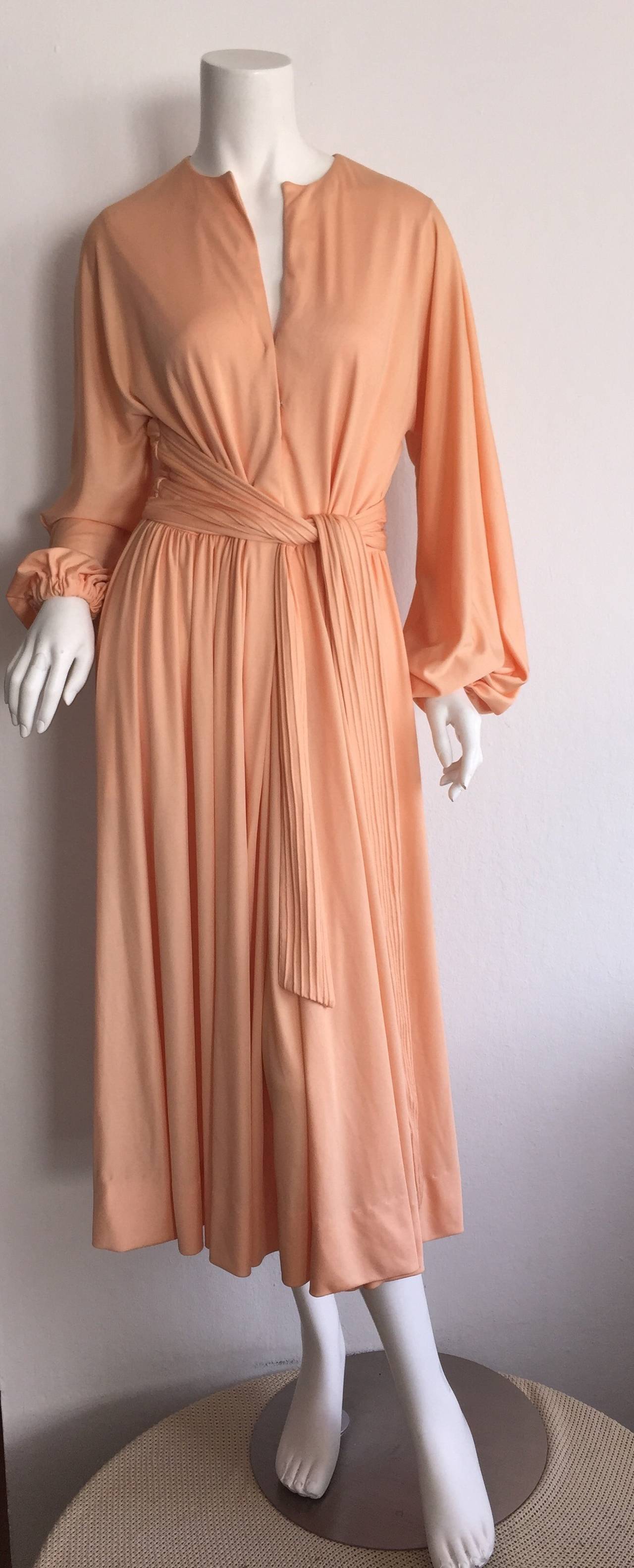 Gorgeous vintage Donald Brooks coral colored jersey wrap dress! So much detail to this flattering frock! Attached pleated wrap belt gives so much slimming detail to the back. Wonderful billow sleeves make for the perfect romantic effect. Can easily