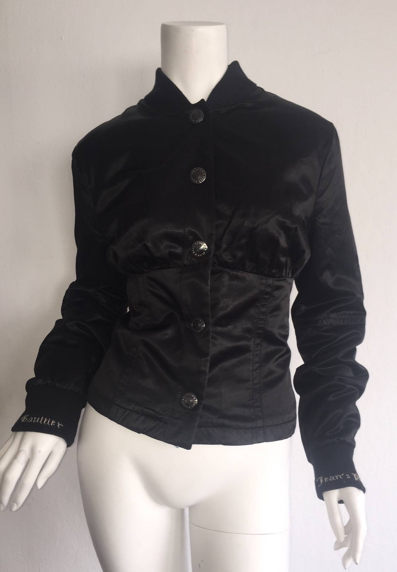 Awesome 1990s vintage Jean Paul Gaultier black bomber jacket! Features lace-up corset back. Signature Gaultier buttons, and tag on back. Gaultier logo at cuffs. Snaps up the front. The perfect everyday jacket! In great condition. Made in Italy.