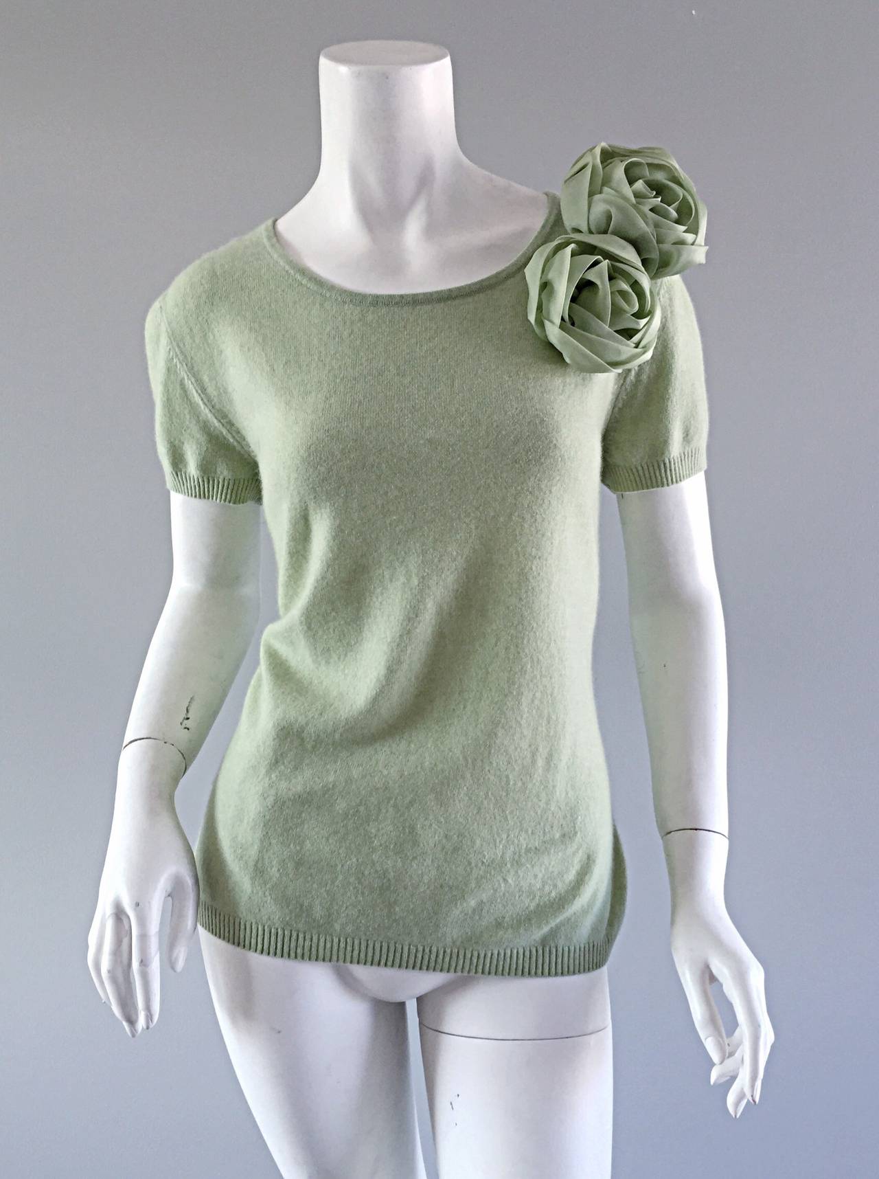 Beautiful Escada short sleeve cashmere sweater! Light green color, with silk rosettes (flower appliqués) at side shoulder. Extremely soft cashmere that is great all year. Perfect alone, or with a blouse under. In great condition. Marked Size EU