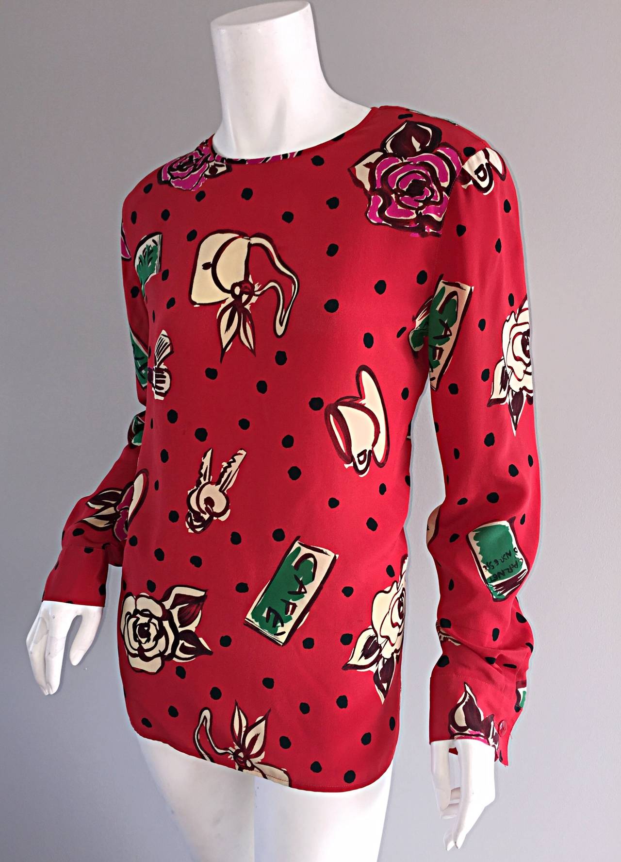 Absolutely amazing vintage Emanuel Ungaro red silk blouse! Features novelty prints of keys, purses, lipstick, flowers, etc. throughout. Buttons up the back. Perfect to transition from day to night. Looks great with shorts or denim, or chic tucked