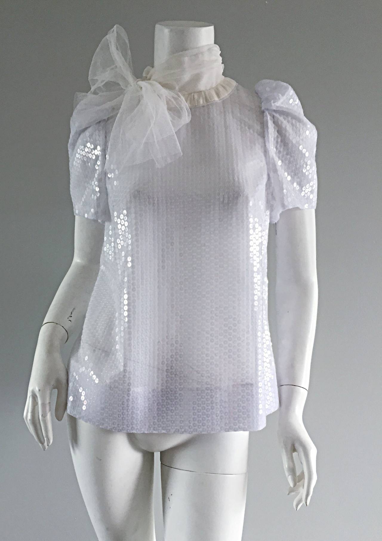 Adorable brand new Peter Som white silk blouse, featuring white sequins throughout. Amazing trapeze / babydoll fit, that is very forgiving/flattering! Oversized white bow, constructed of layers of white gauze. Cute puff sleeves. Chic mother of pearl