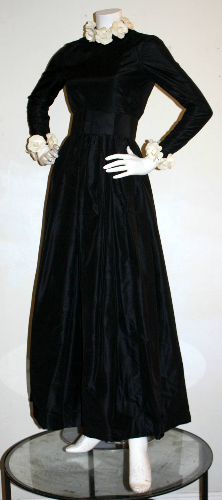 Rare vintage beauty by Bill Blass! Black silk taffeta, with white silk Camellia flowers adorning the entire neckline, and sleeve cuffs. Stunning open back. Comes with original matching belt. In great condition. Approximately Size